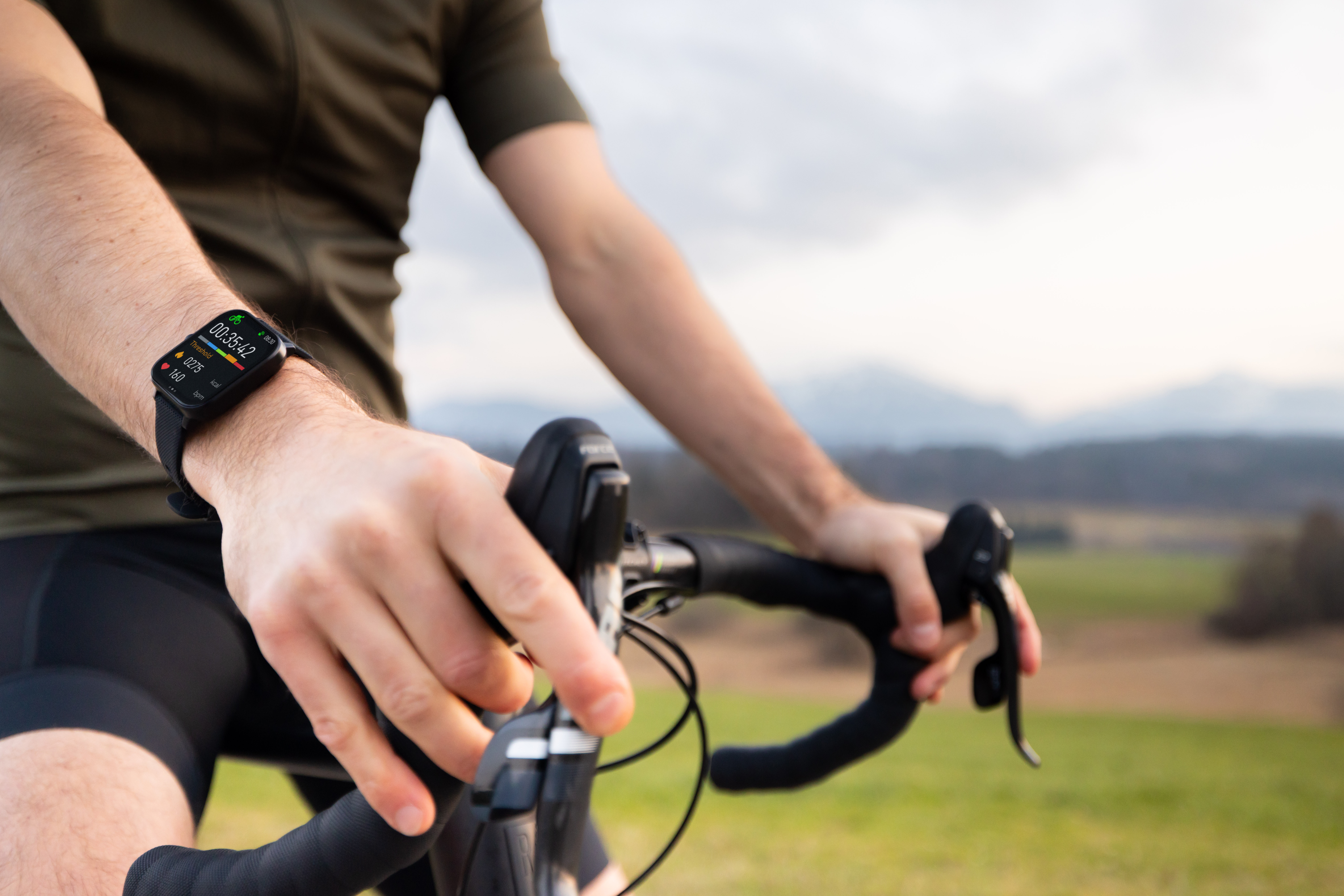 Ein Radfahrer trägt eine Smartwatch, die Zeit, Kalorien und Herzfrequenz anzeigt.