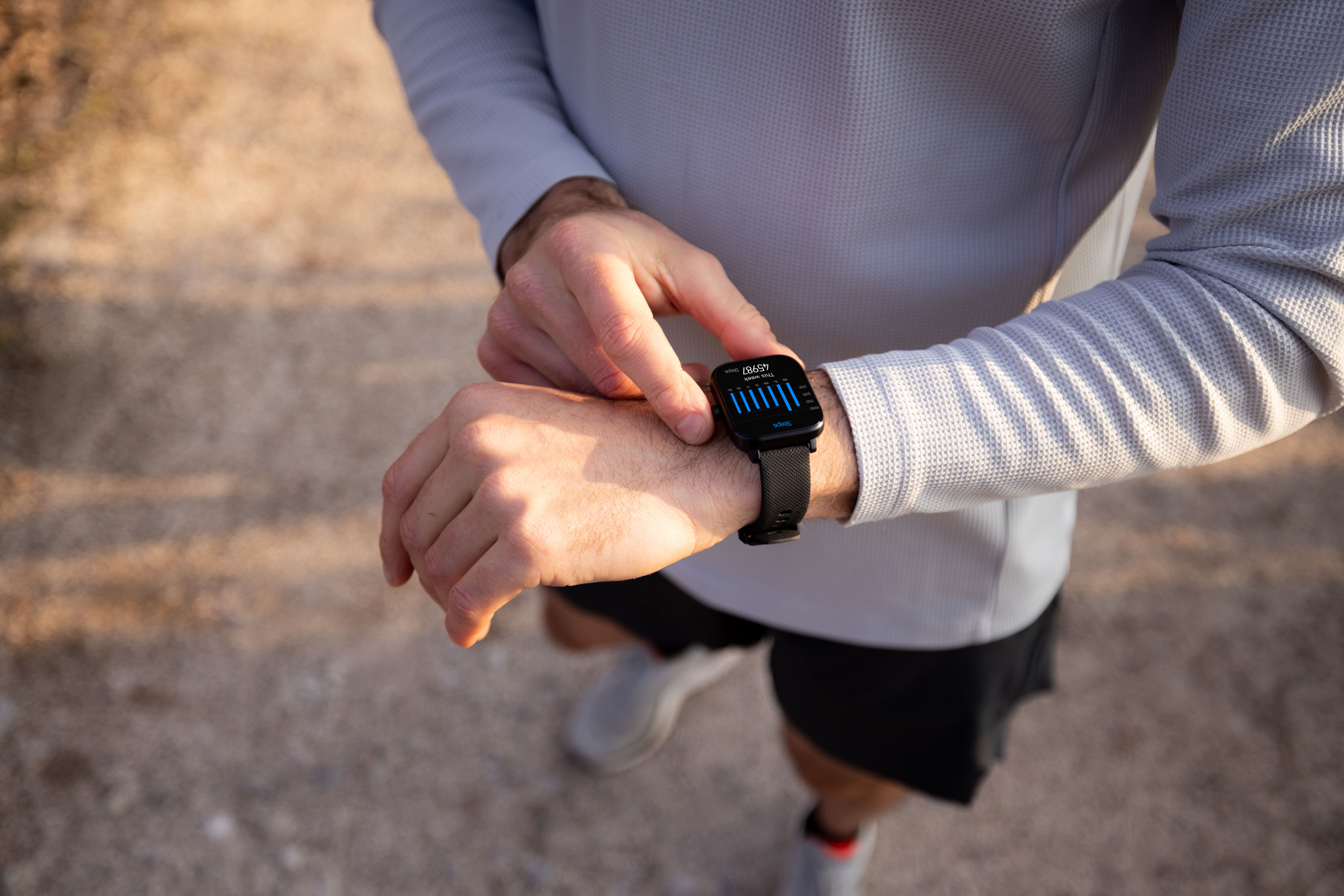 Mann berührt seine Smartwatch mit Schrittzähler-Anzeige auf dem Handgelenk.