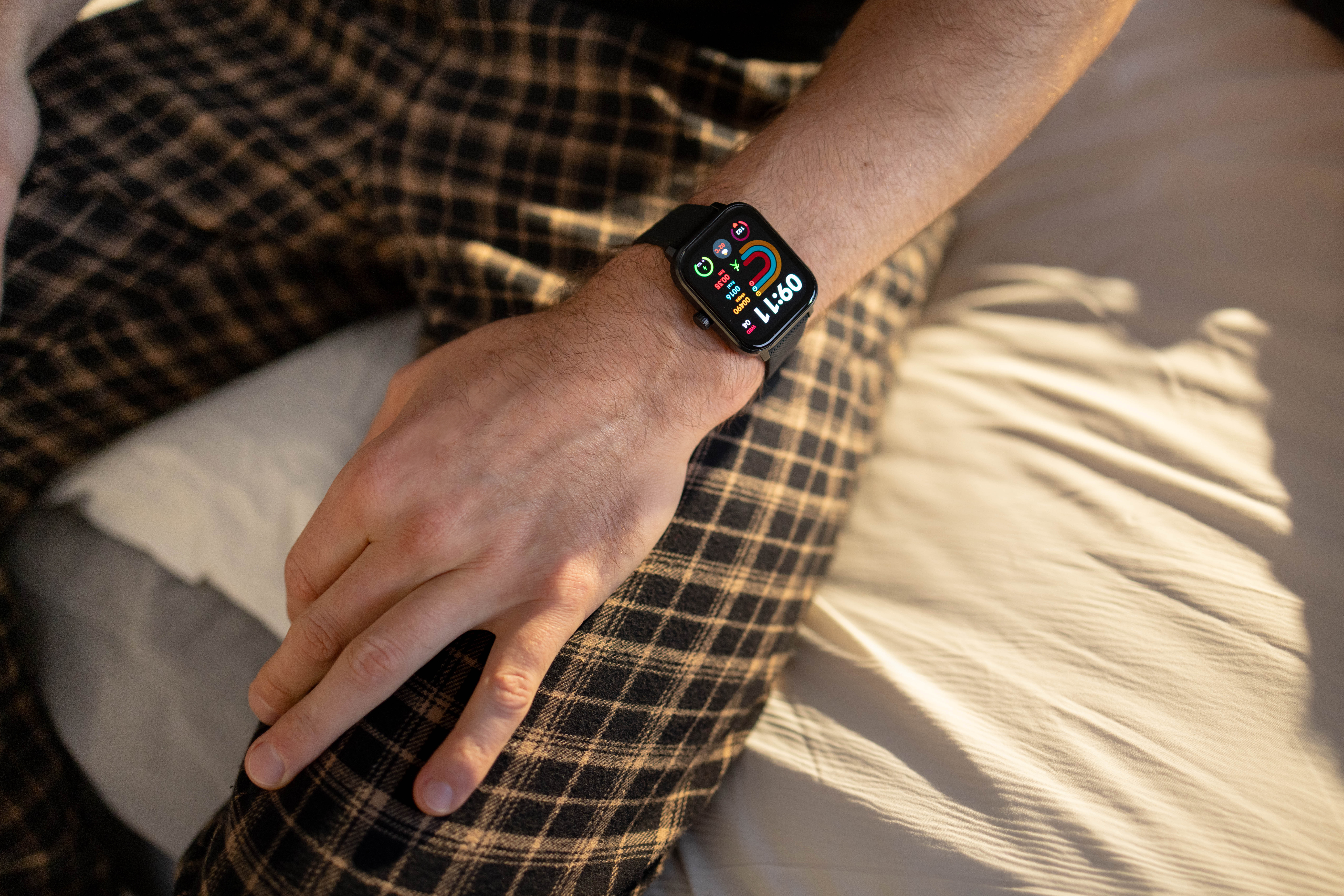 Eine Person trägt eine Smartwatch auf ihrem linken Handgelenk. Sie trägt karierte Hose.