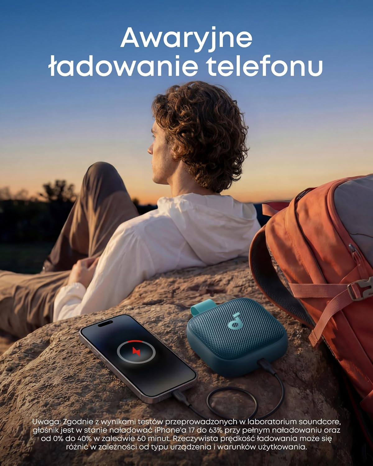Mężczyzna siedzi na zewnątrz, jego telefon ładuje się z powerbanku.