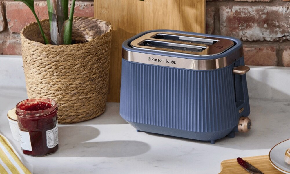 Niebieski toster Russell Hobbs na marmurowym blacie obok słoika dżemu.