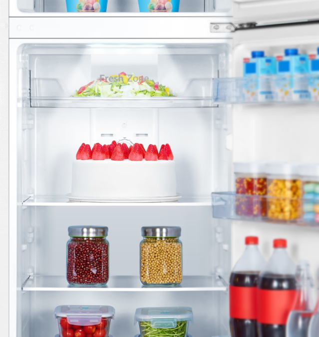 Un refrigerador abierto con pastel, ensalada, frascos y bebidas dentro.