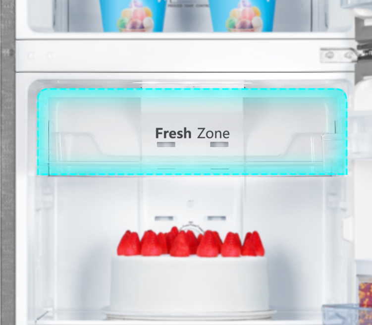 Un compartimento de refrigerador etiquetado "Fresh Zone" con un pastel cubierto de fresas.