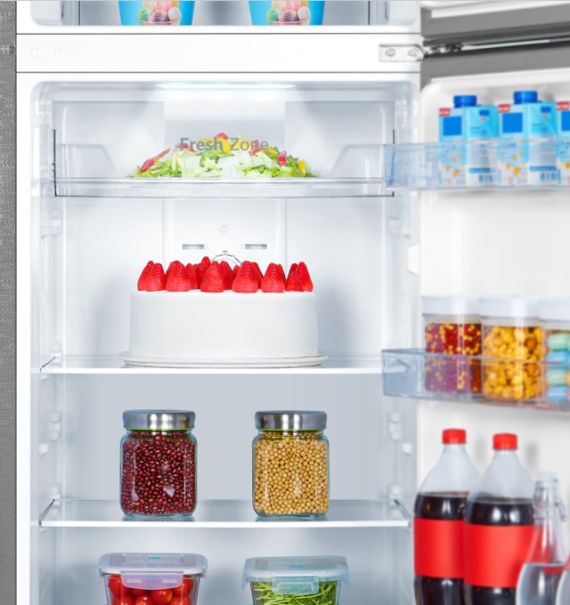 Un refrigerador abierto con pastel, ensalada y bebidas.