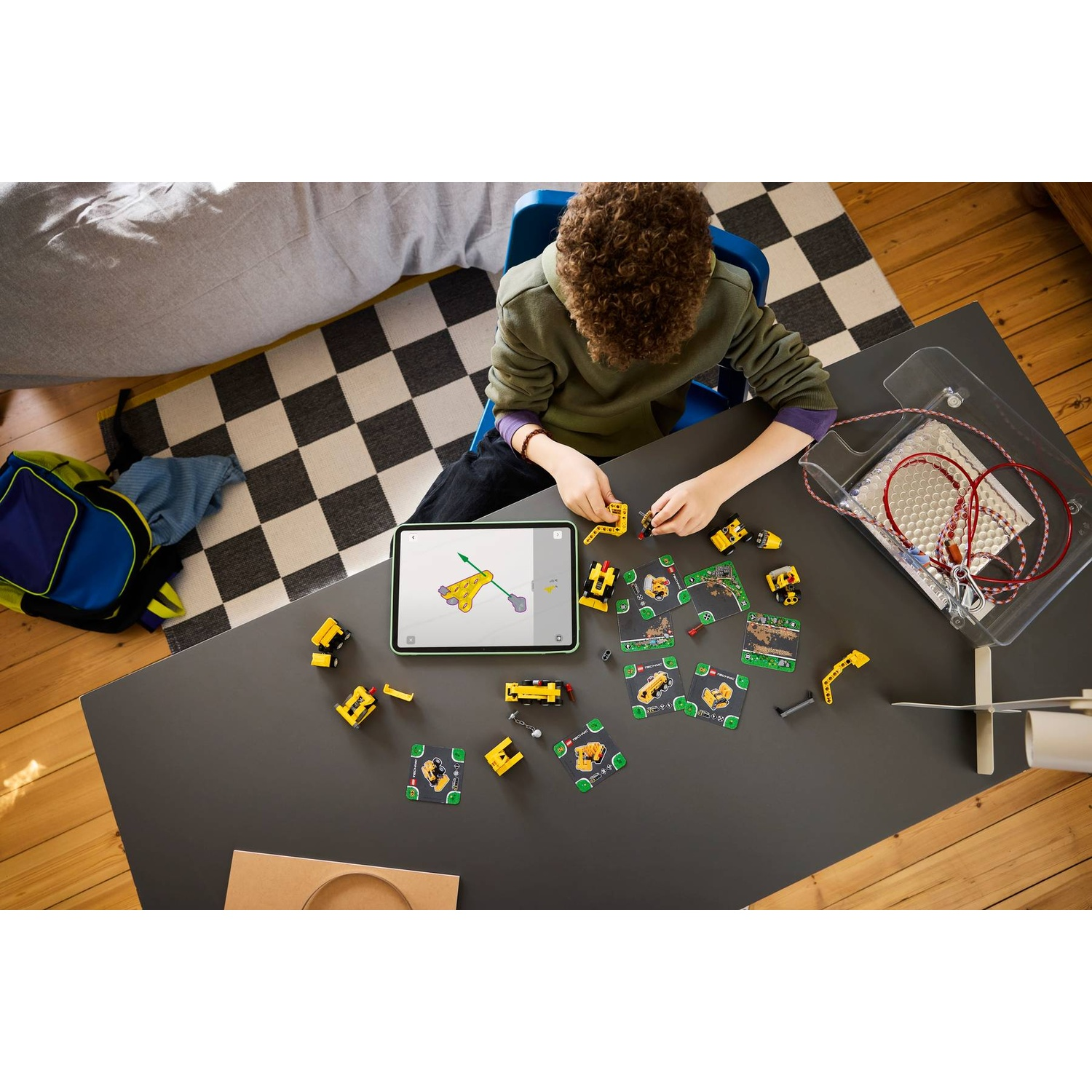 Un ragazzo costruisce con mattoncini Lego gialli e un'app su un tavolo.