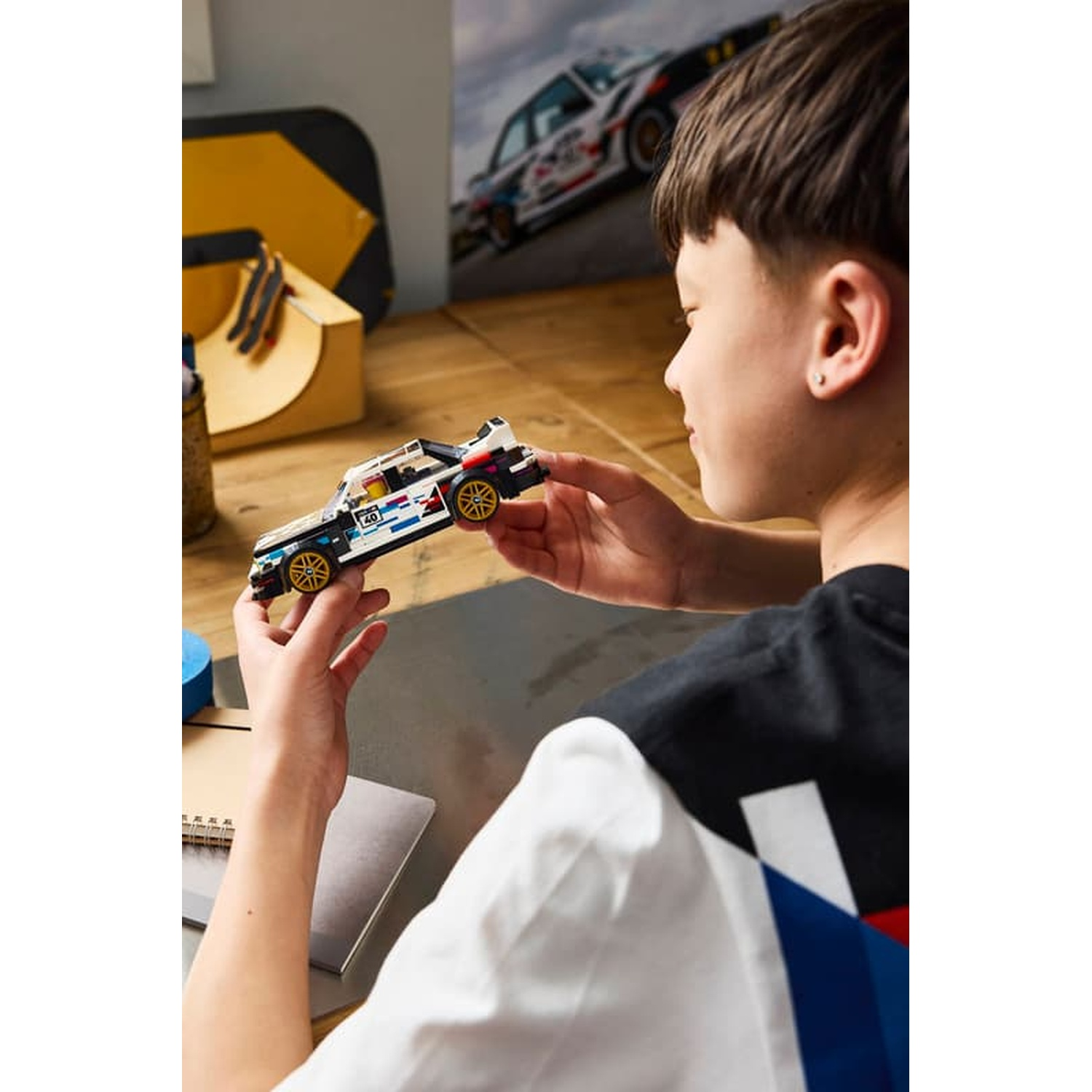 Un ragazzo tiene un'auto modello Lego. Uno sfondo con rampa e skateboard.