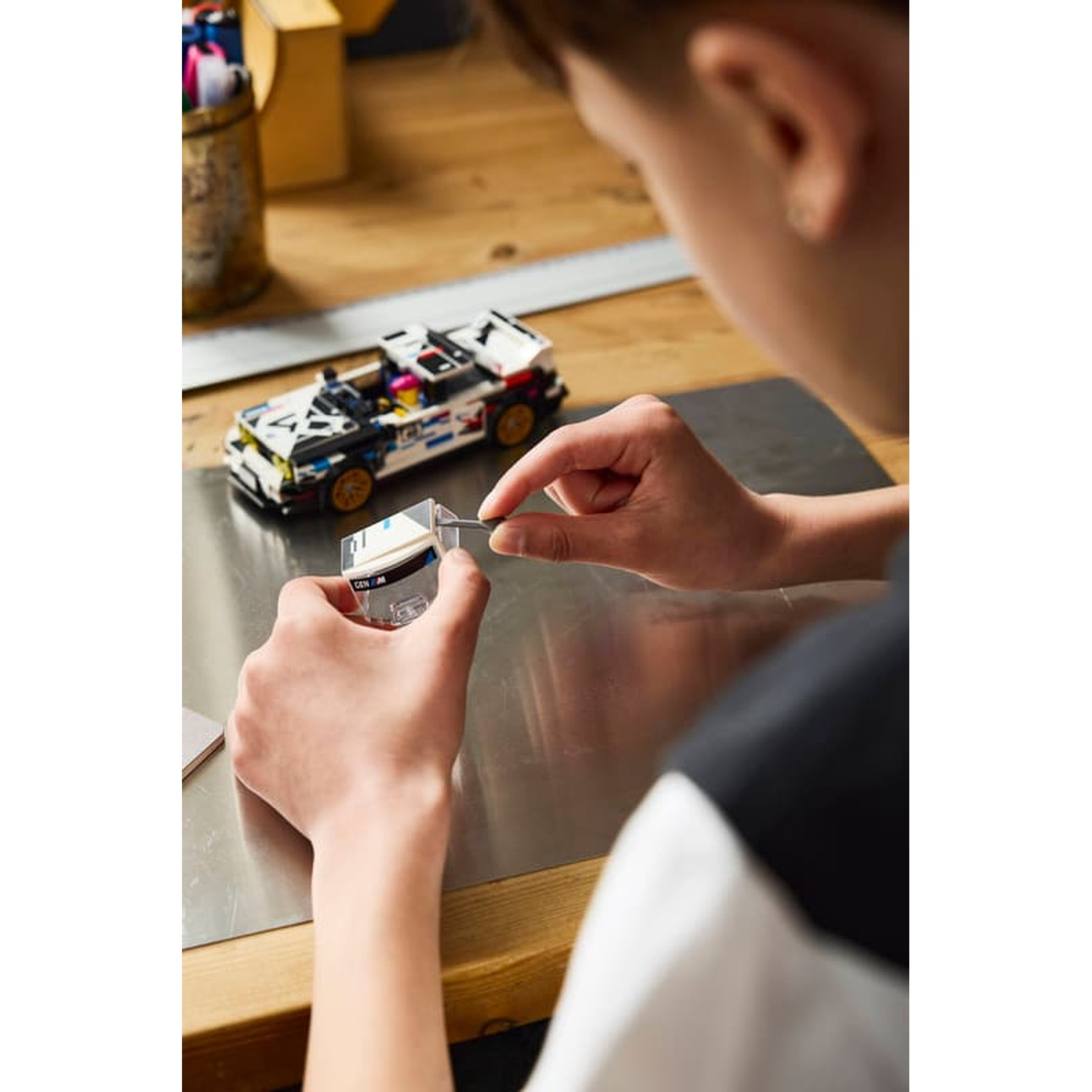 Persona costruisce un modello di auto Lego bianco e blu. Mani tengono una piccola parte.