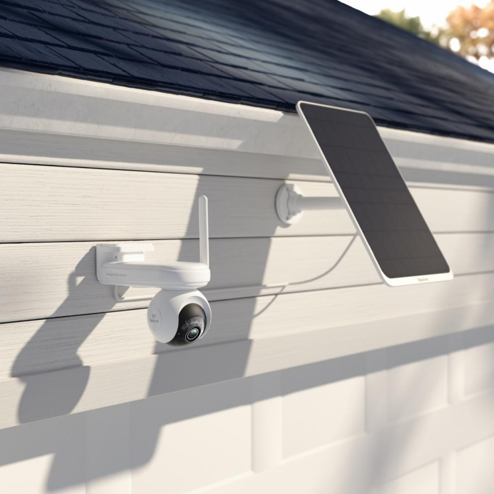Weiße Überwachungskamera mit Solarpanel an Hauswand montiert.
