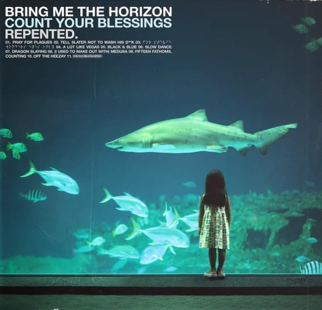 Ein Mädchen betrachtet einen Hai und Fische in einem Aquarium.
