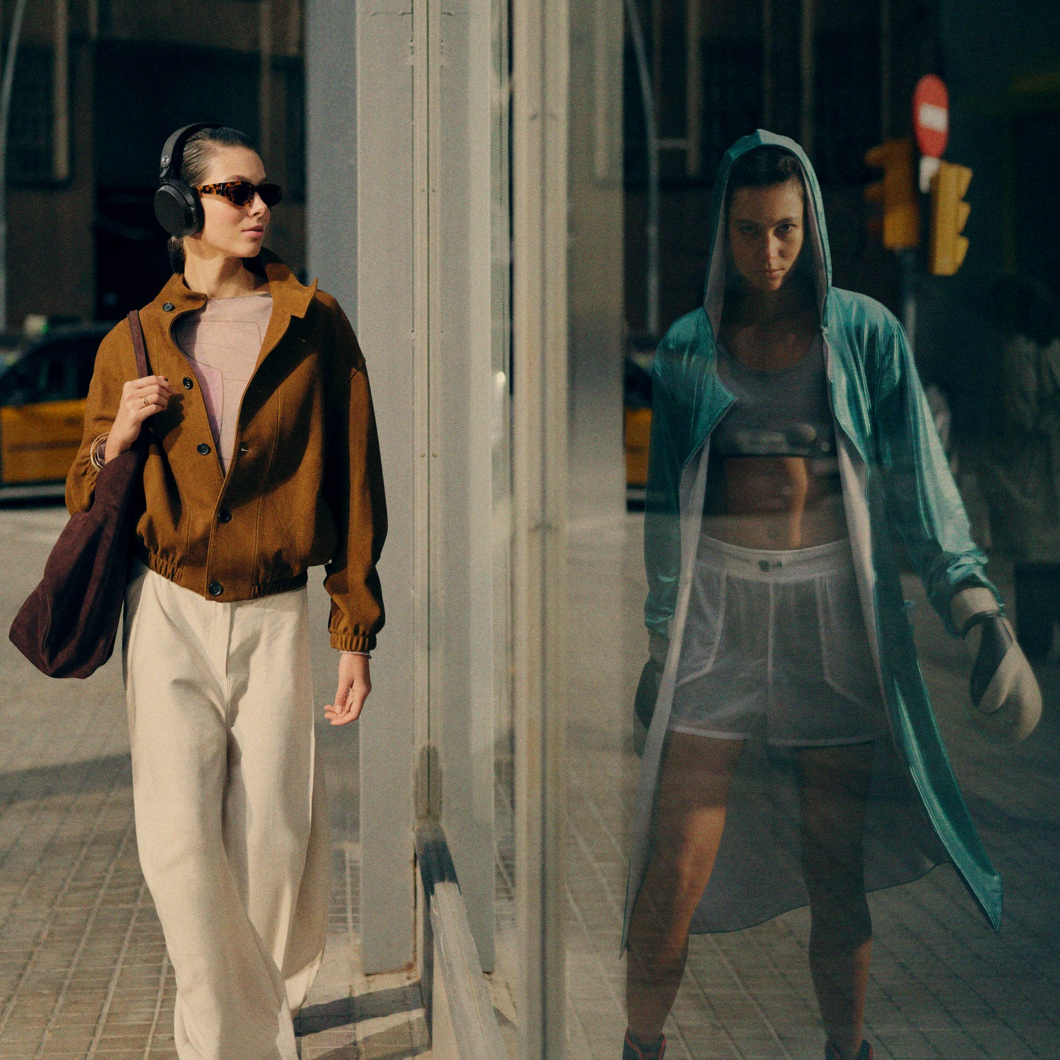 Woman in brown jacket walks past a window reflecting a boxer in a blue robe.