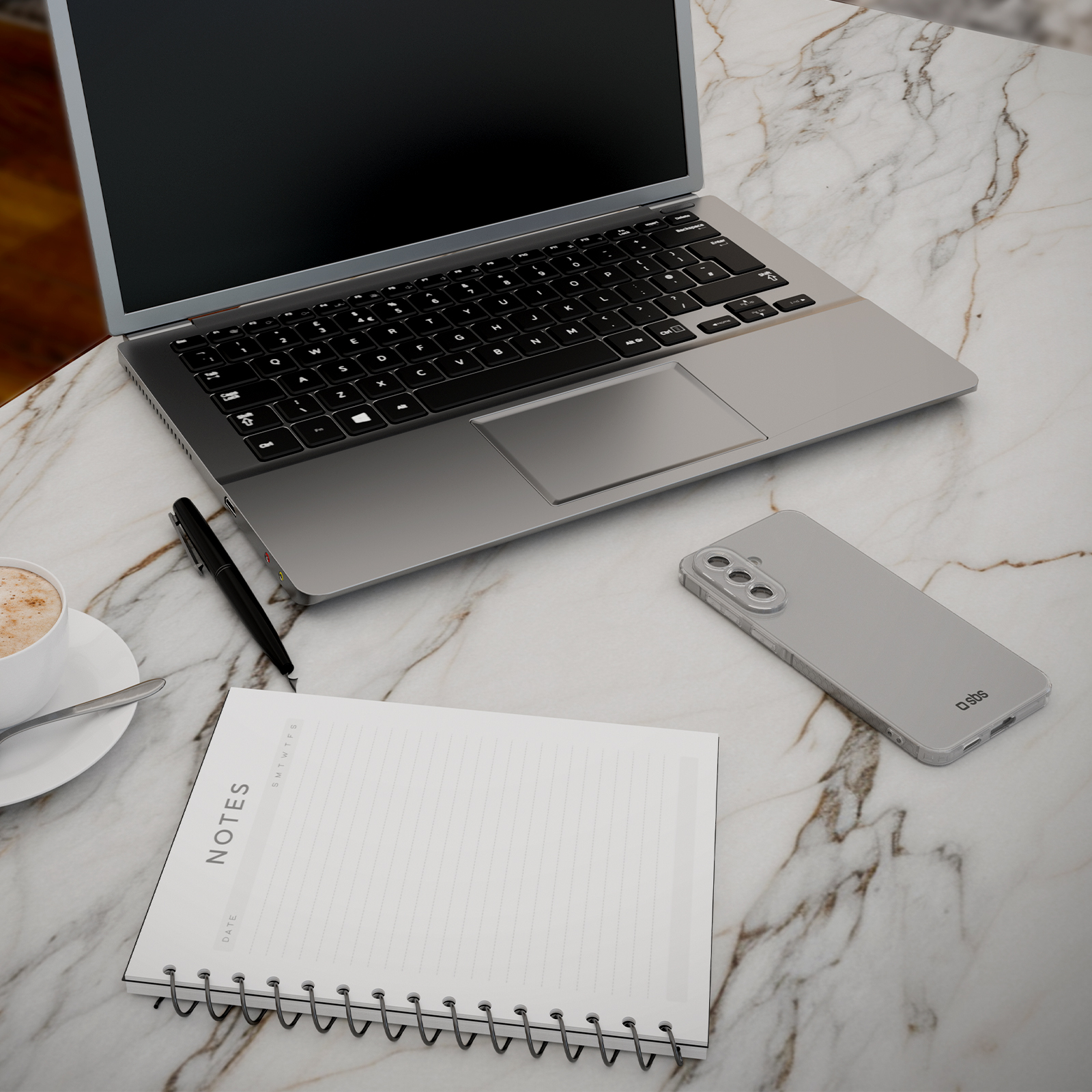 Ein Laptop, Notizbuch, Stift, Kaffee und Handy liegen auf Marmor.