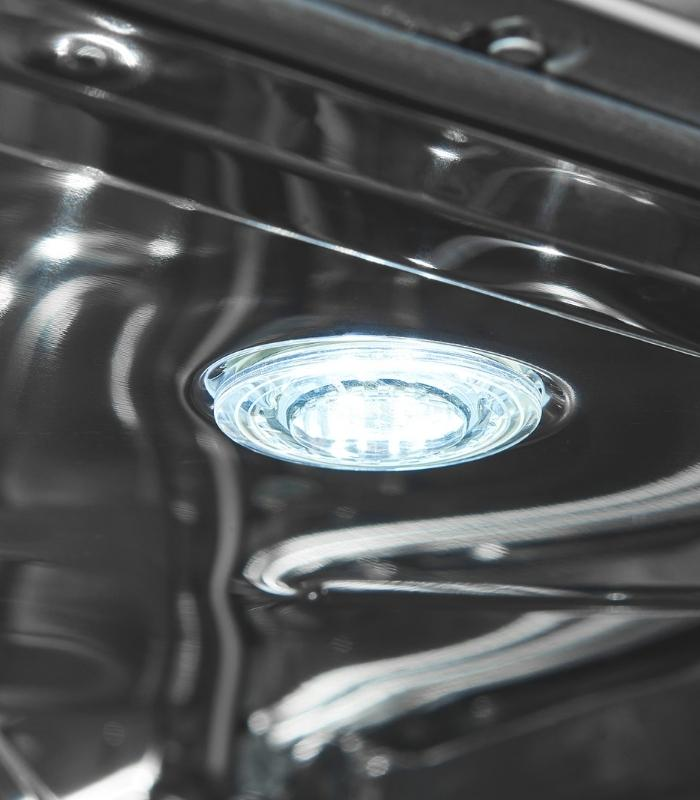 Ein helles LED-Licht leuchtet aus einer klaren Fassung auf einer dunklen, reflektierenden Oberfläche.