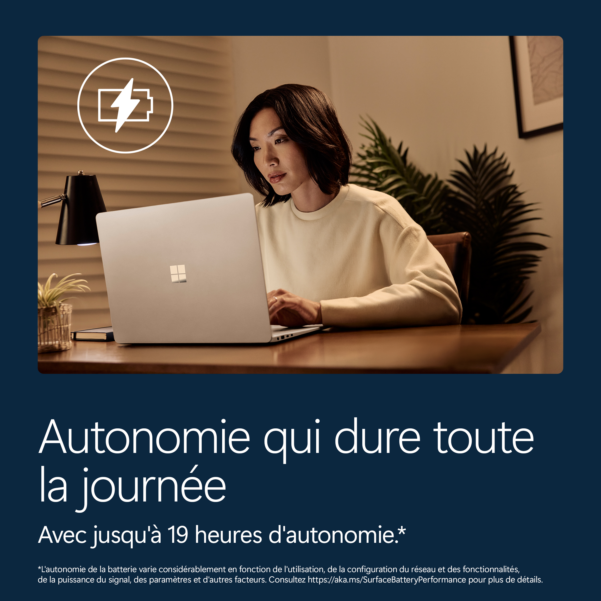 Une femme travaille sur un ordinateur portable. Une icône de batterie est en haut à gauche.