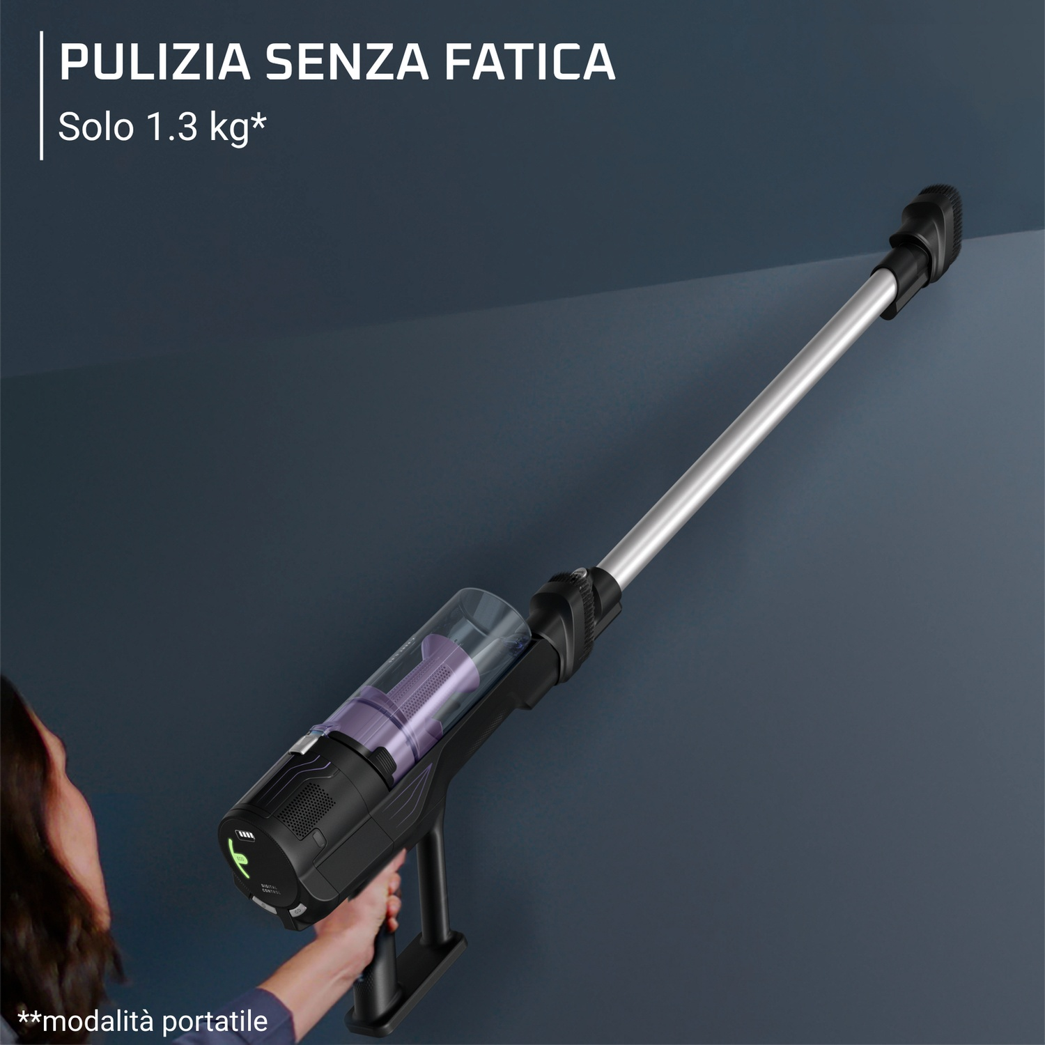 Aspirapolvere nero portatile con tubo argento e spazzola su sfondo grigio.