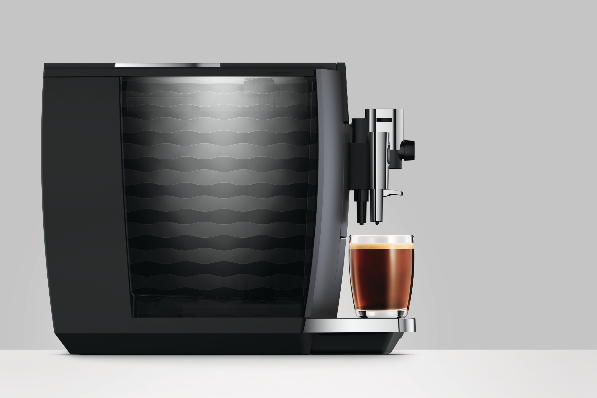 Eine schwarze Kaffeemaschine brüht Kaffee in ein Glas.
