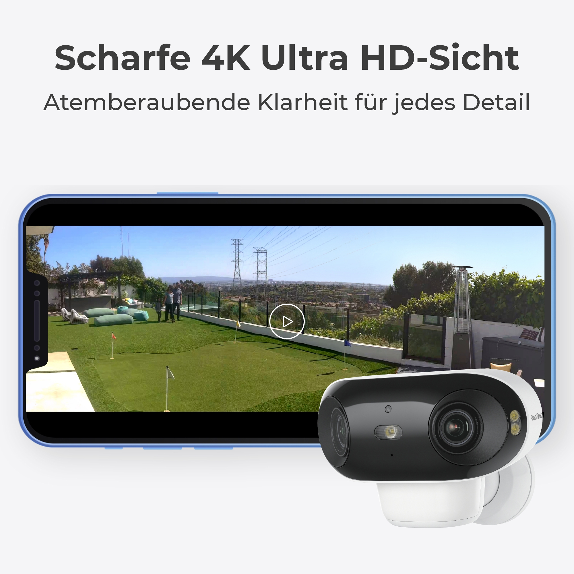 Eine Überwachungskamera zeigt eine Außenansicht mit Rasen, Fahnen und Strommasten.