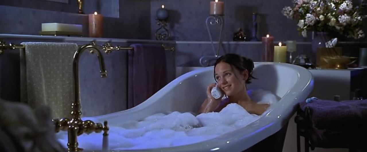 Eine Frau telefoniert in einer schaumgefüllten Badewanne.