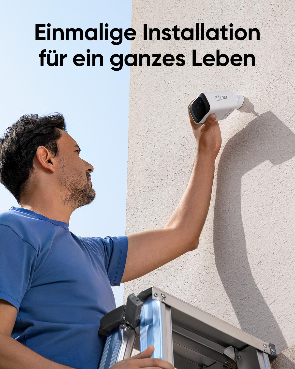 Mann montiert Überwachungskamera an Hauswand, steht auf Leiter.