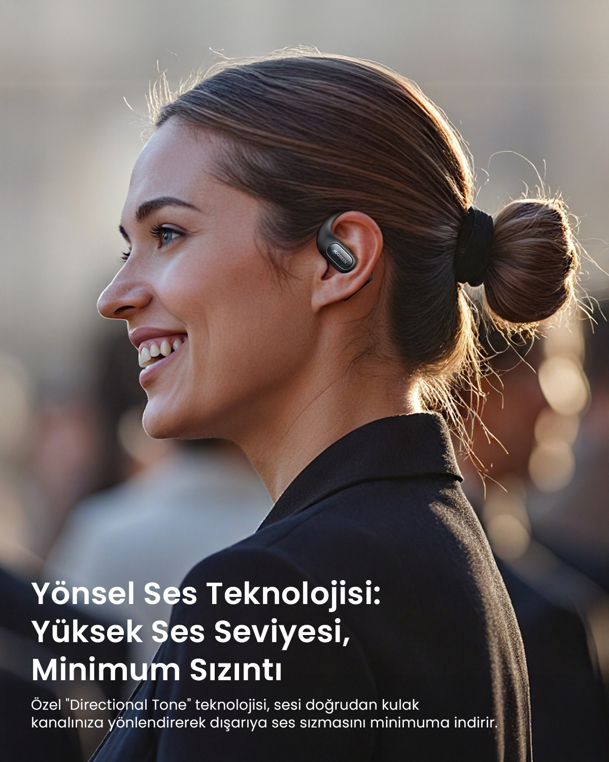 Kulaklıkla bir kadın sola doğru gülüyor. Arka plan bulanık.