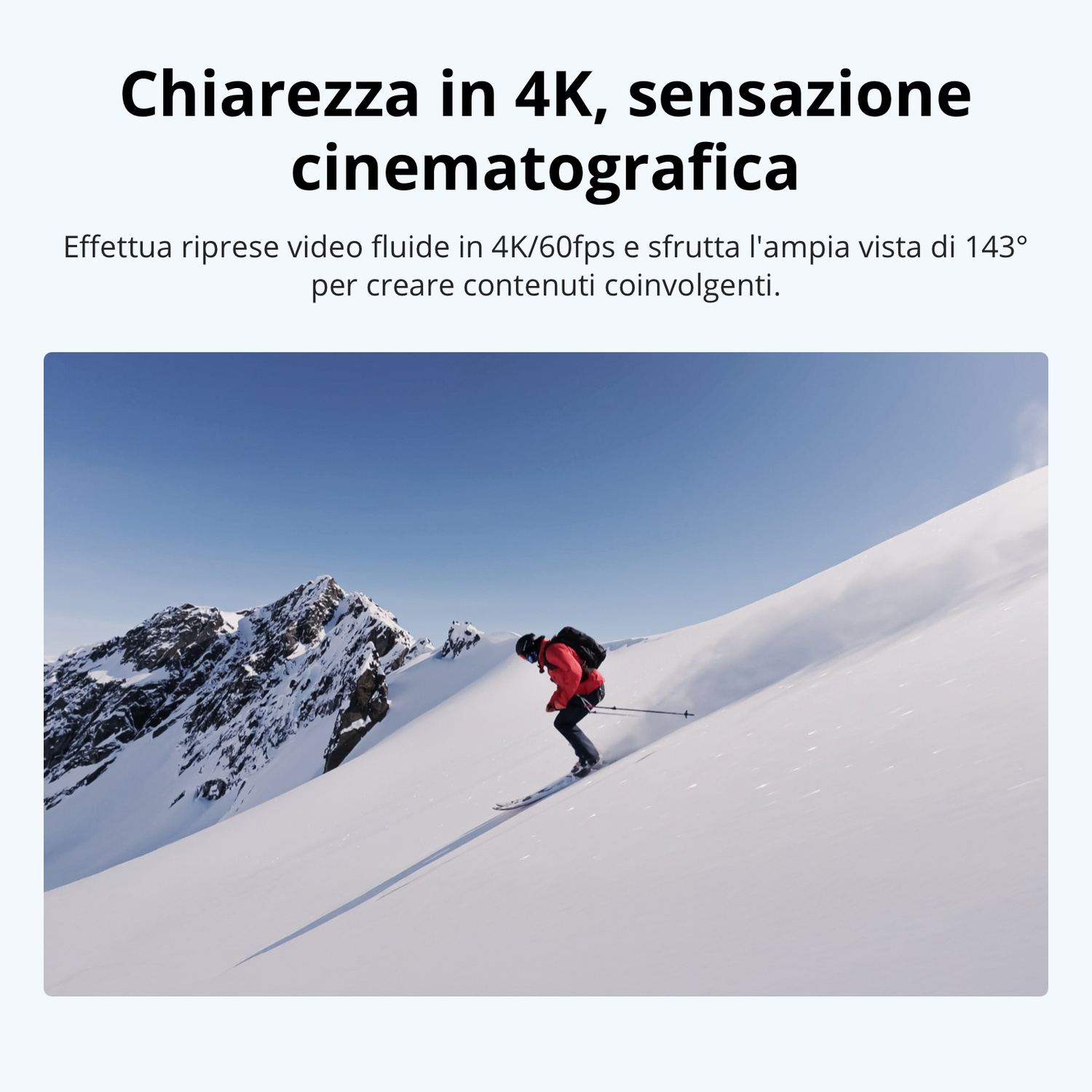 Uno sciatore con giacca rossa scia su un pendio innevato, montagne sullo sfondo.