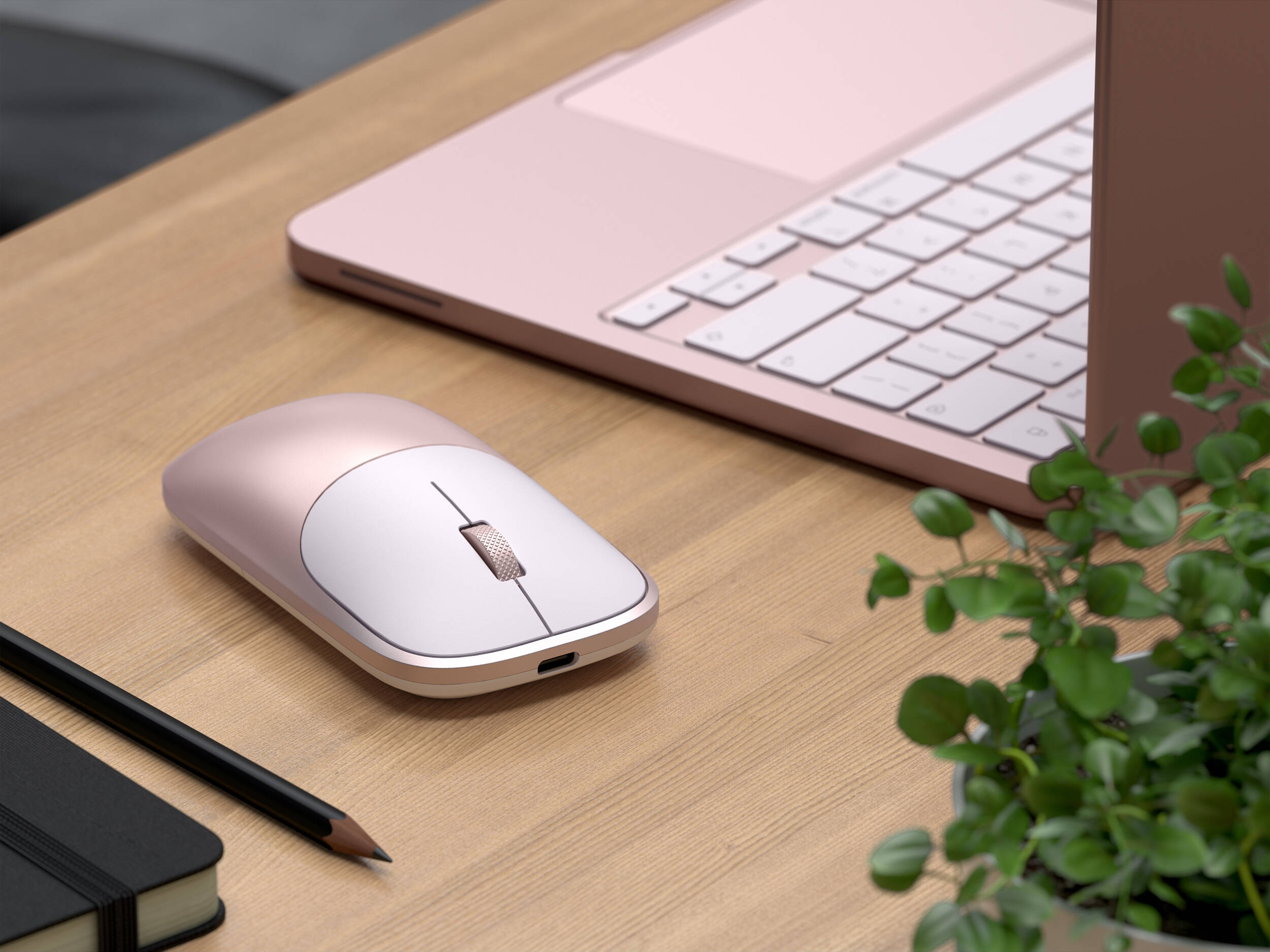 Un ordinateur portable, une souris, un carnet et un crayon en or rose sur un bureau.