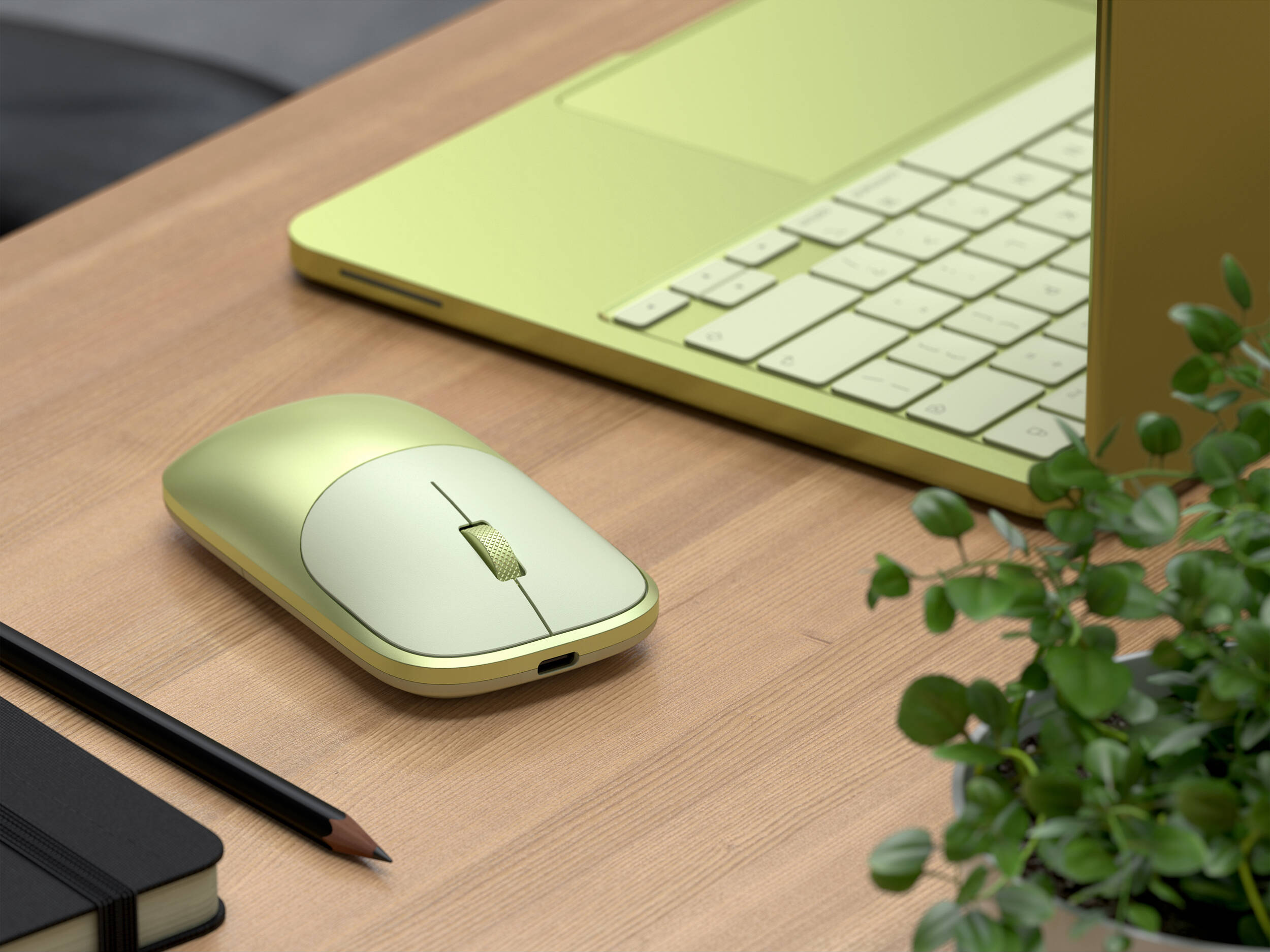 Un ordinateur portable vert clair, une souris, un carnet et un crayon sur un bureau en bois.