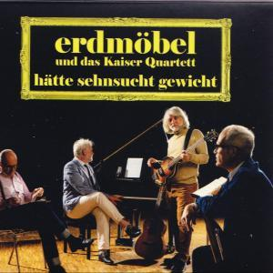 Vier Männer in einem Raum. Einer spielt Gitarre, die anderen sitzen.