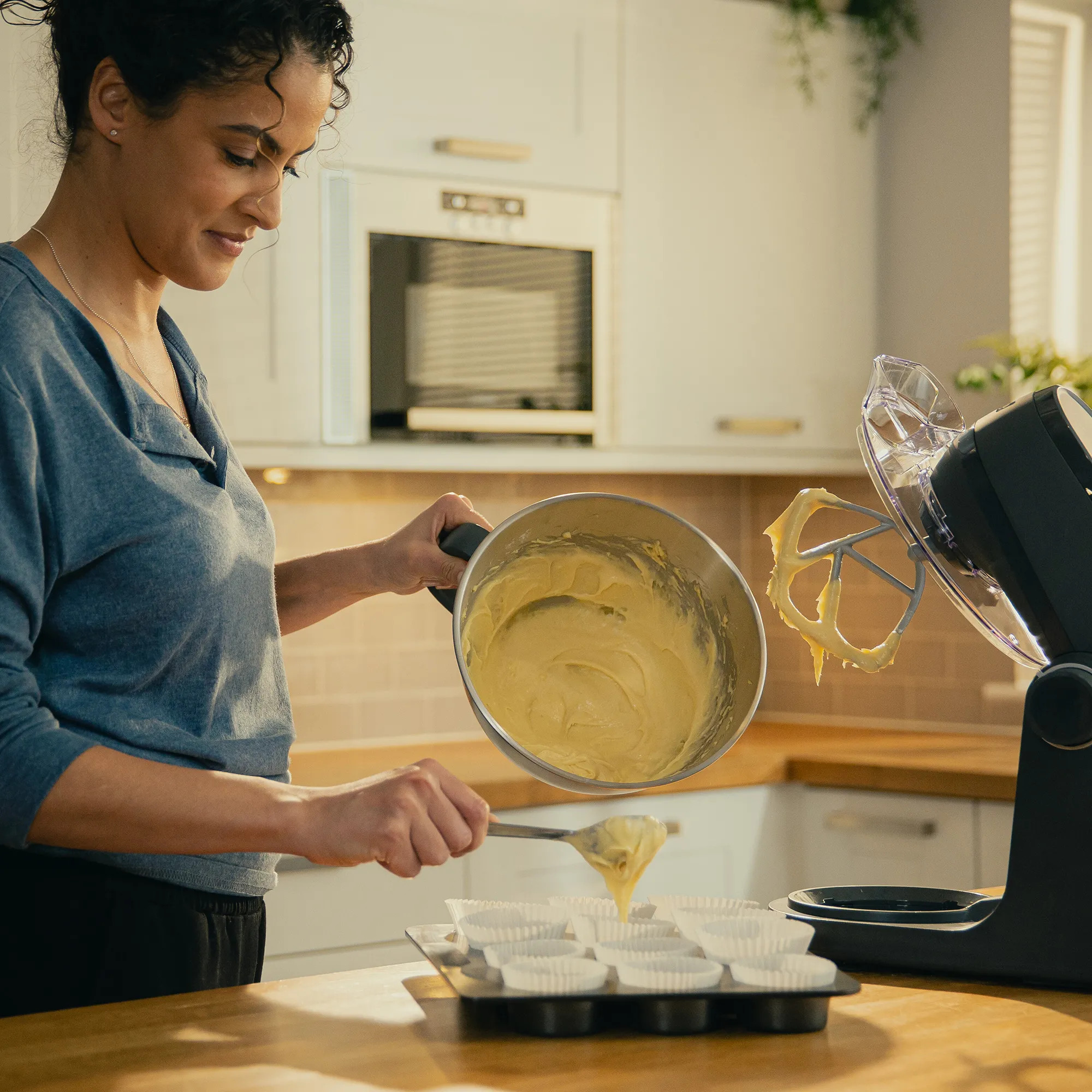 Kobieta nakłada ciasto z miski do papilotek na muffiny.