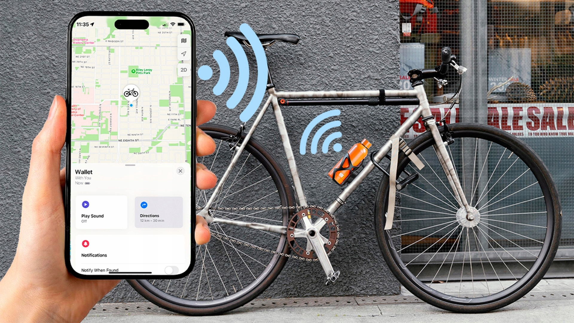 Ręka trzyma smartfon z aplikacją mapy. Obok stoi rower.