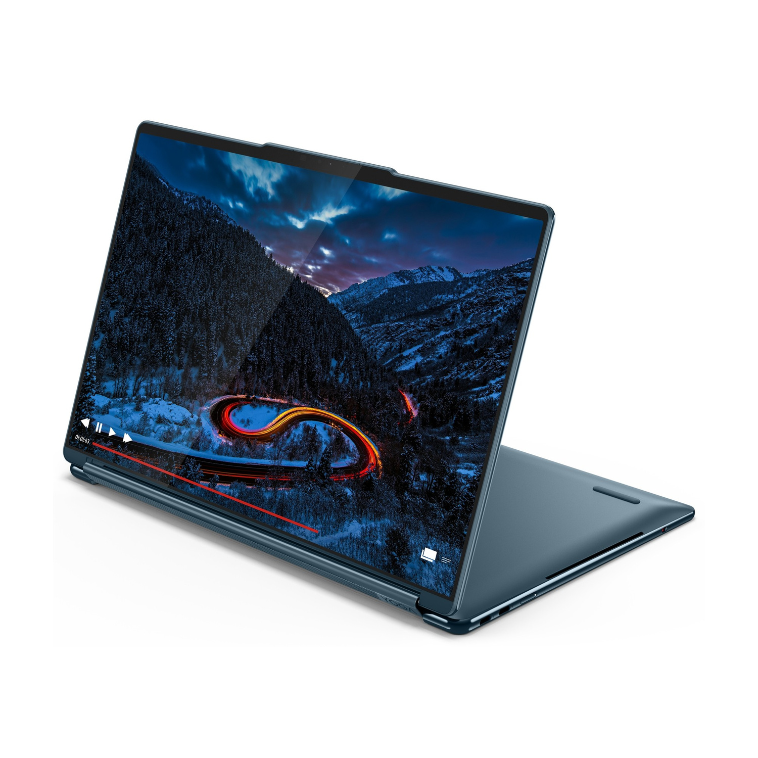 Un laptop blu mostra un video di una strada tortuosa attraverso una foresta innevata al crepuscolo.