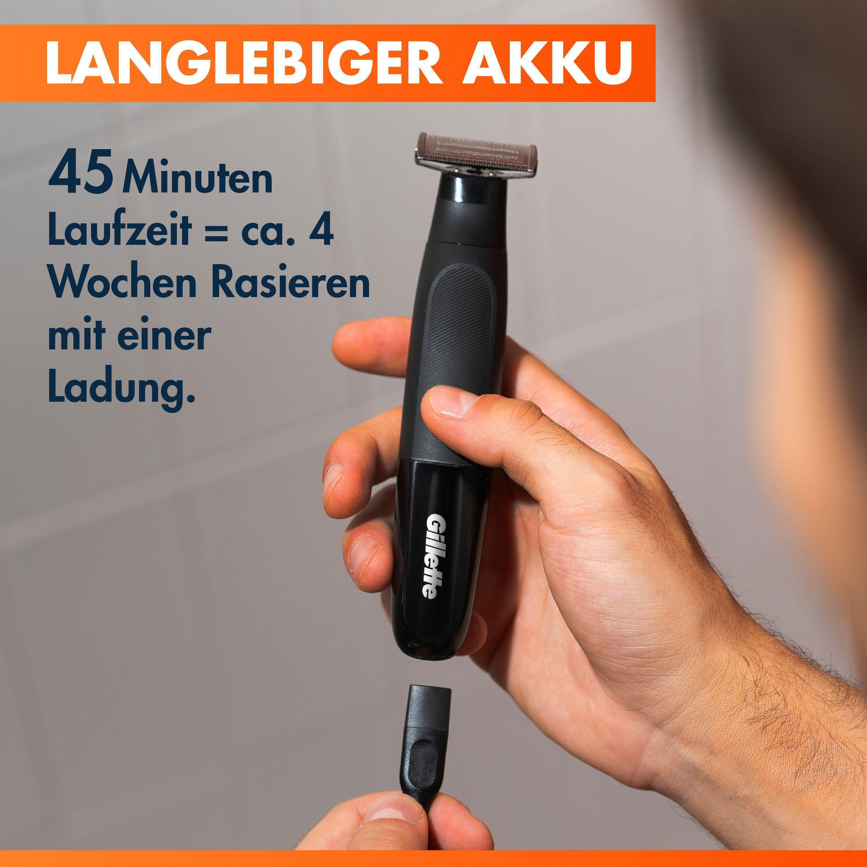 Ein Mann hält einen schwarzen Gillette Rasierer mit Aufsatz und Ladekabel.