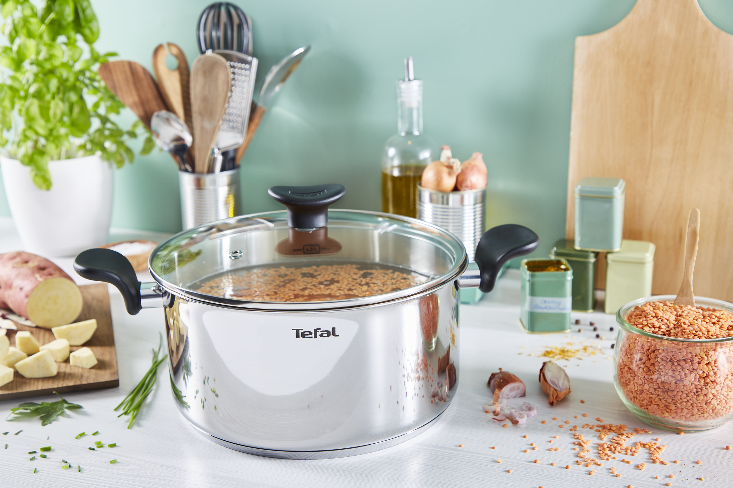 Una olla Tefal con lentejas, batata y utensilios de cocina.