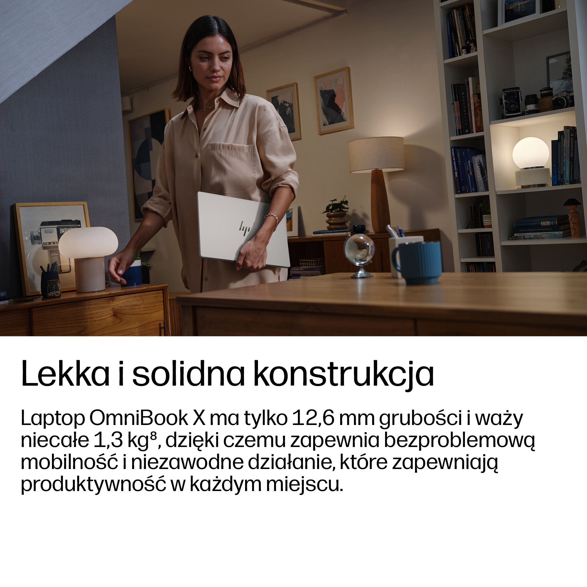 Kobieta trzyma laptopa w biurze z książkami i lampami.