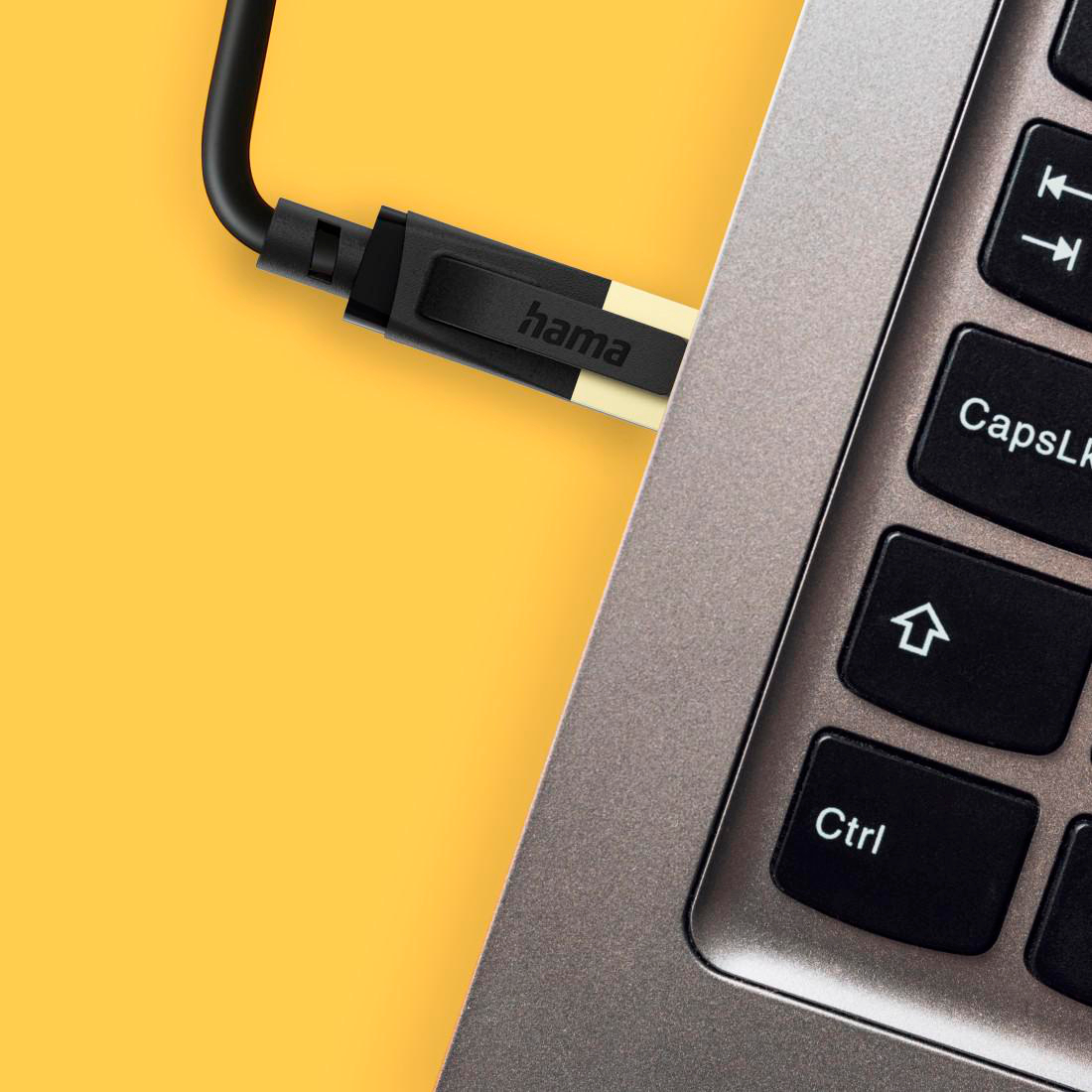 Ein Hama-Kabel wird in einen Laptop eingesteckt. Gelber Hintergrund.