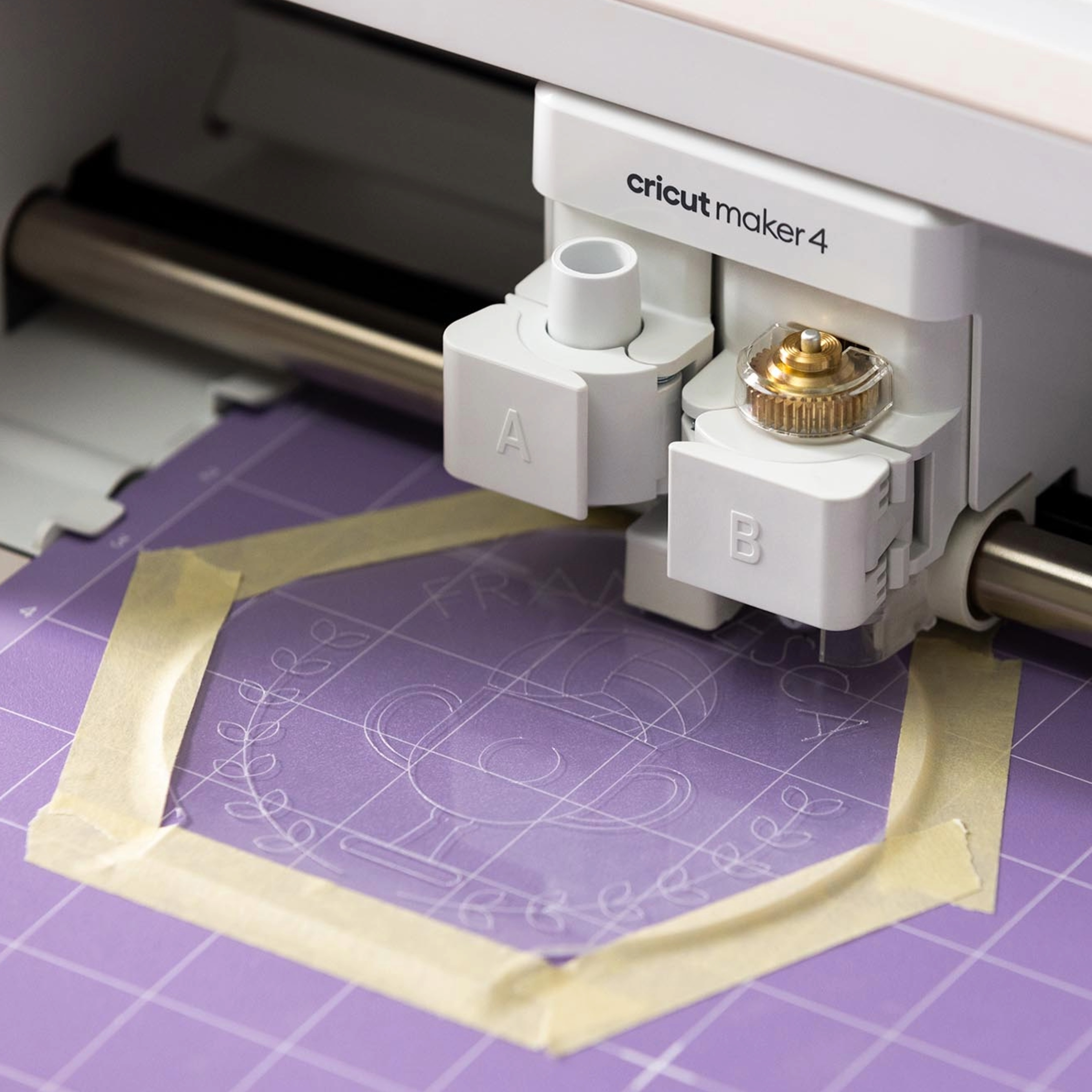 Bir Cricut Maker 4, bantla sabitlenmiş mor bir mat üzerine desen kesiyor.