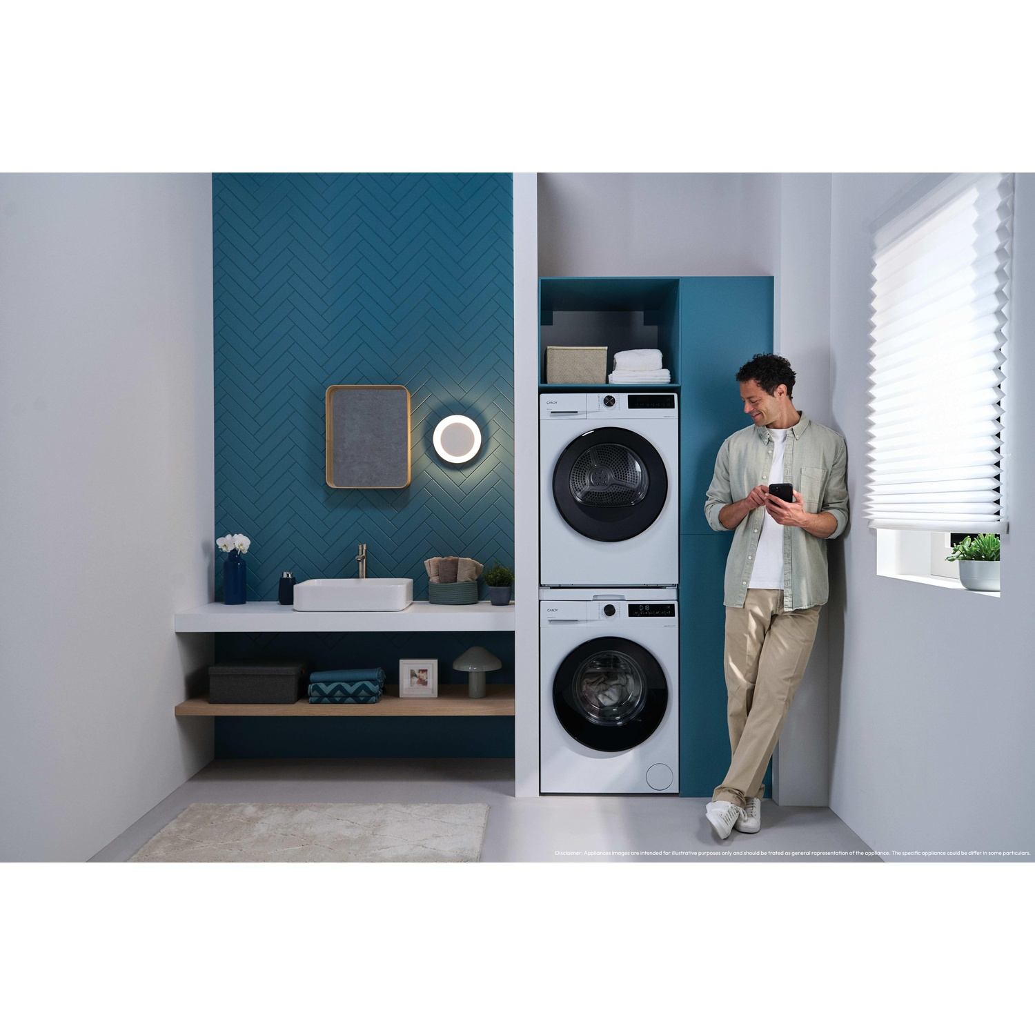A man with a phone stands next to a washer and dryer in a bathroom.