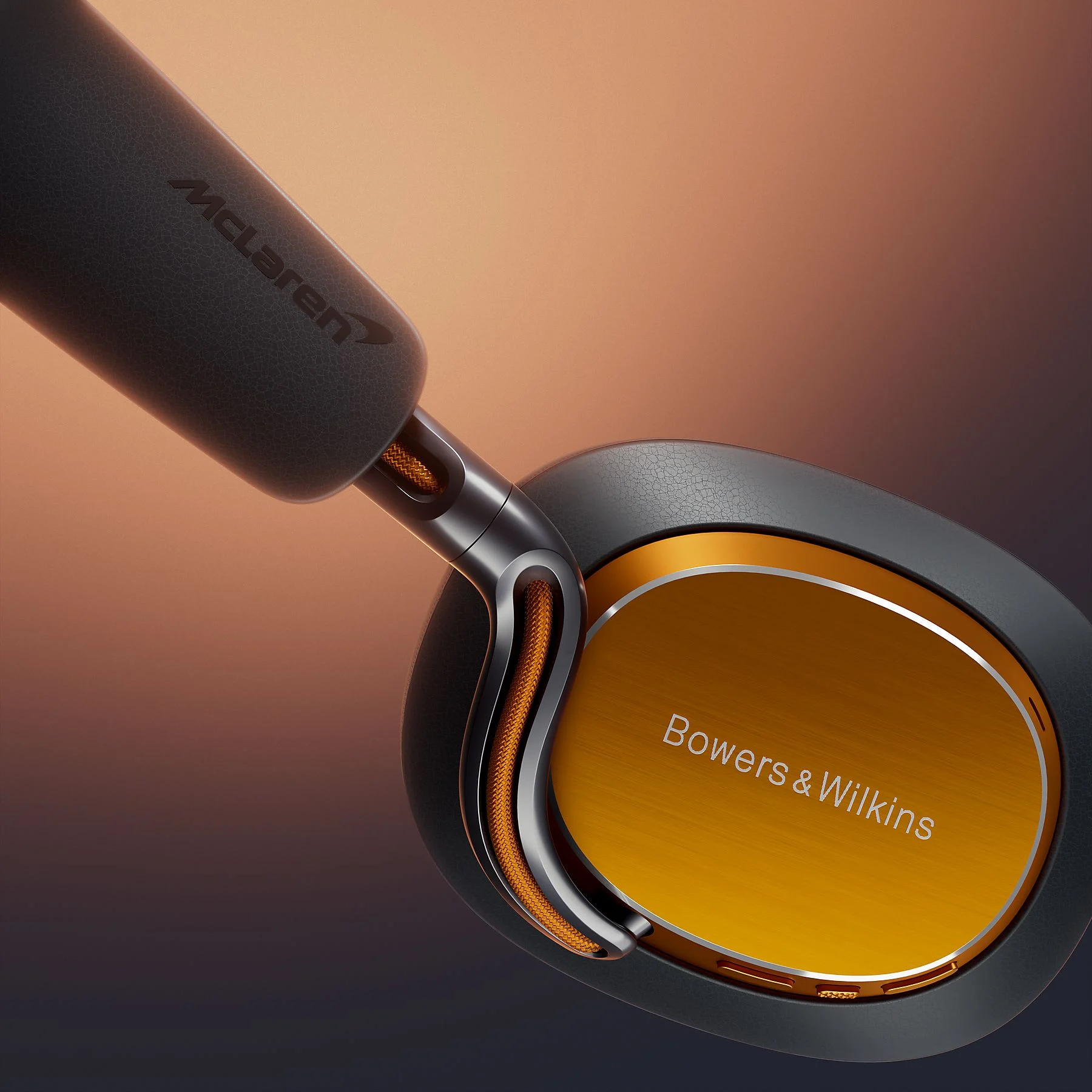 Czarne słuchawki z pomarańczowymi akcentami i logo McLaren.