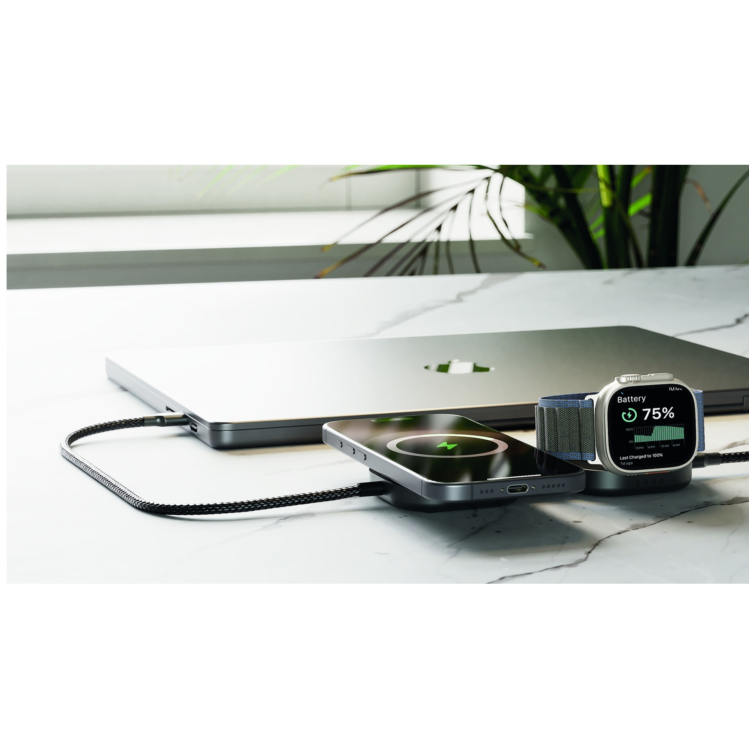 A laptop, smartphone, and smartwatch are charging on a marble surface.