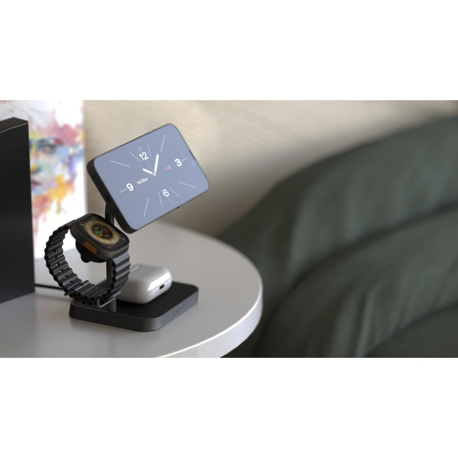 A black multi-device charging stand with a smartwatch, wireless earbuds, and a smartphone displaying a clock, on a white table.
