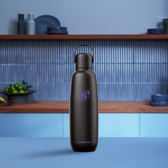 Czarna butelka Sodastream z fioletowym logo na niebieskim stole.