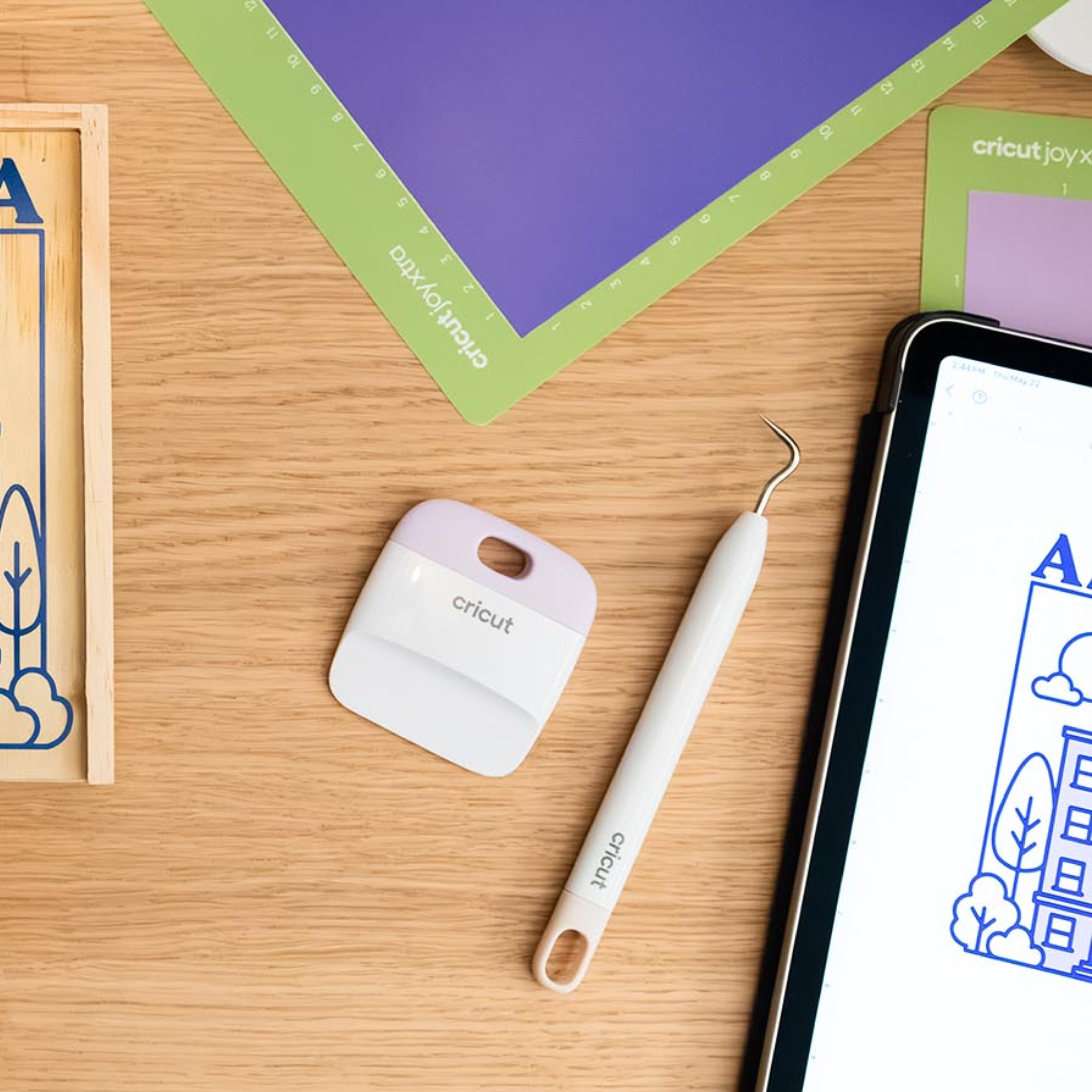 Ahşap masa üzerinde el işi aletleri: kesme matları, kazıyıcı, kanca, tablet.