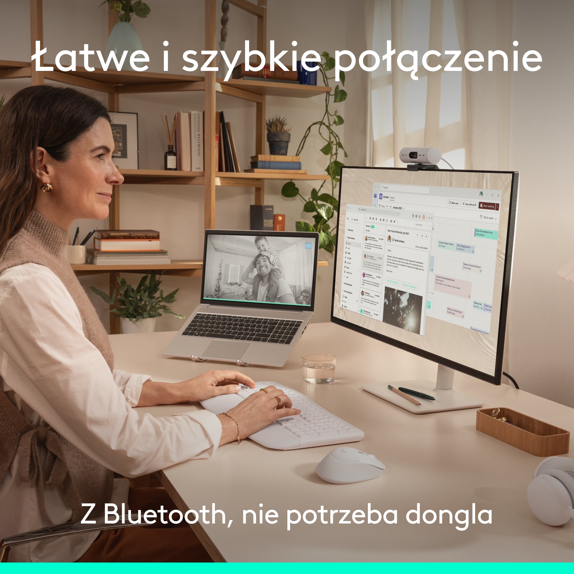 Kobieta siedzi przy biurku z laptopem, monitorem i kamerką internetową.