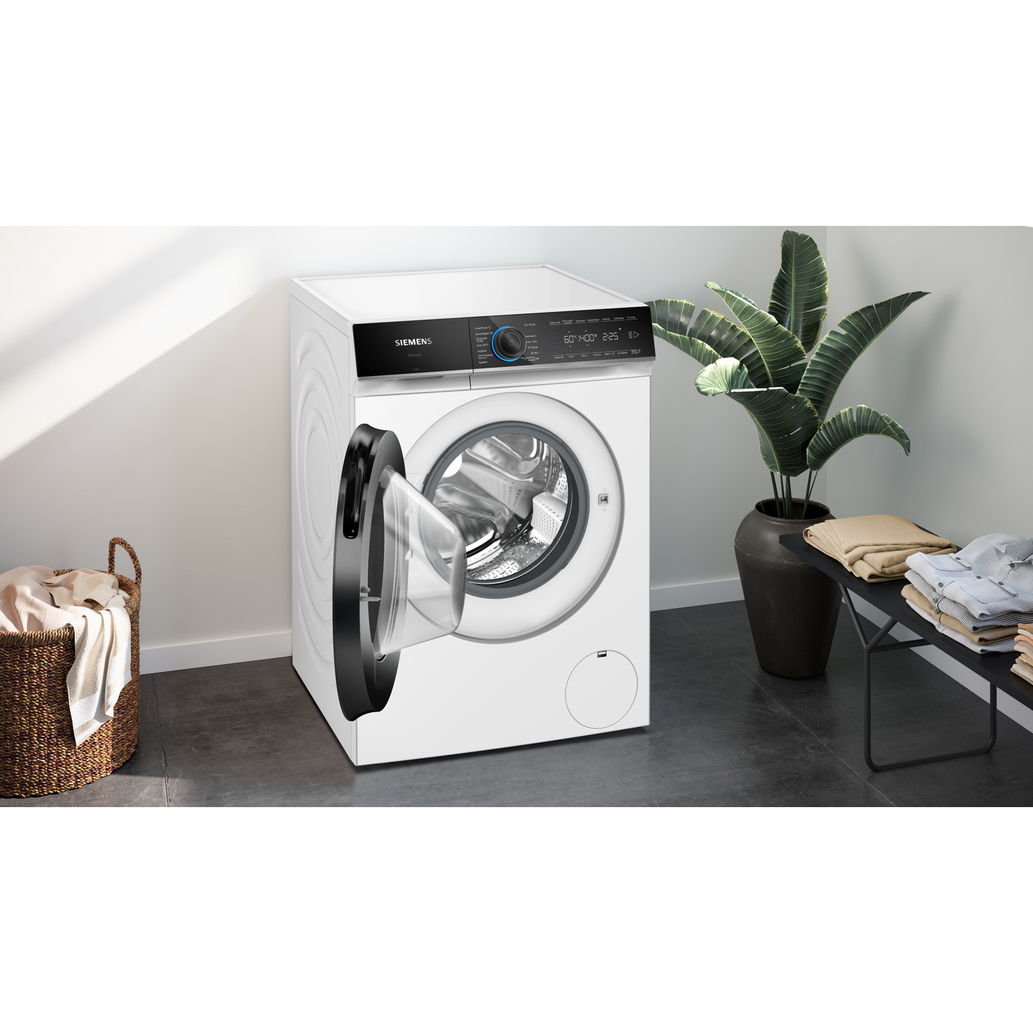 Witte Siemens wasmachine met open deur, wasmand, plant, gevouwen kleding.