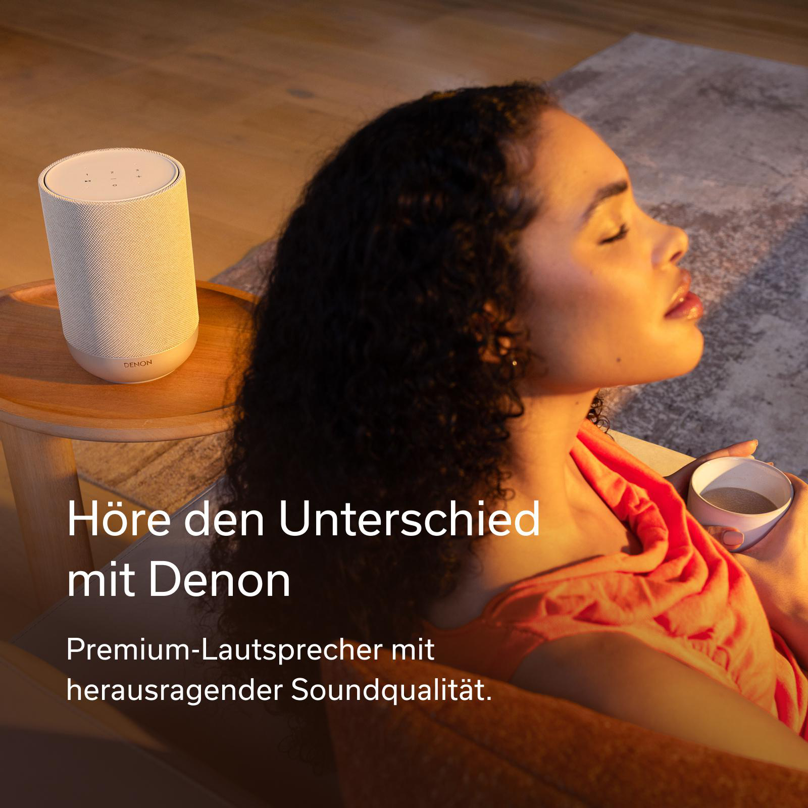 Eine Frau mit dunklen Locken genießt die Sonne, neben einem Denon Lautsprecher.