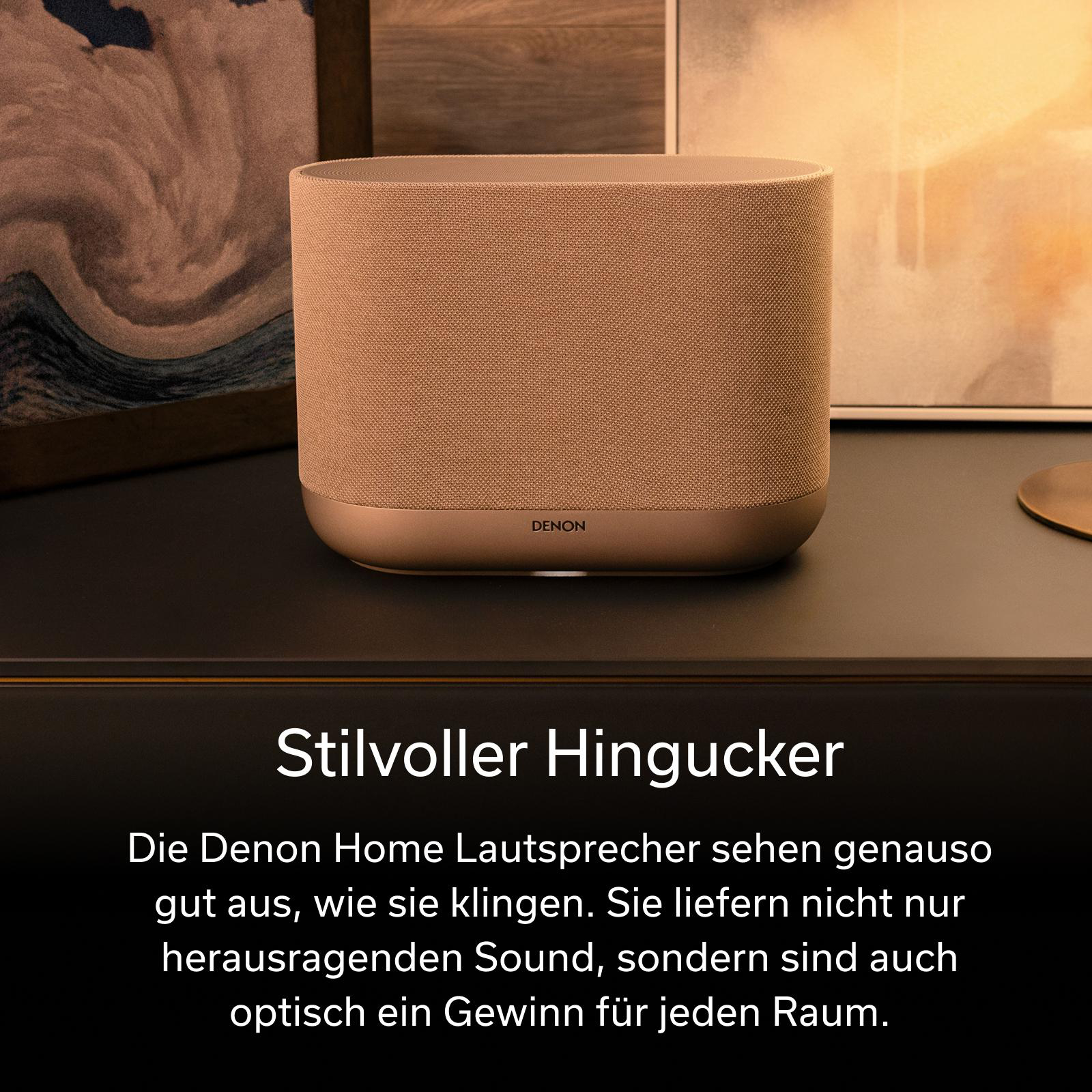 Ein brauner Denon Lautsprecher steht auf einem dunklen Regal, daneben Kunstwerke.