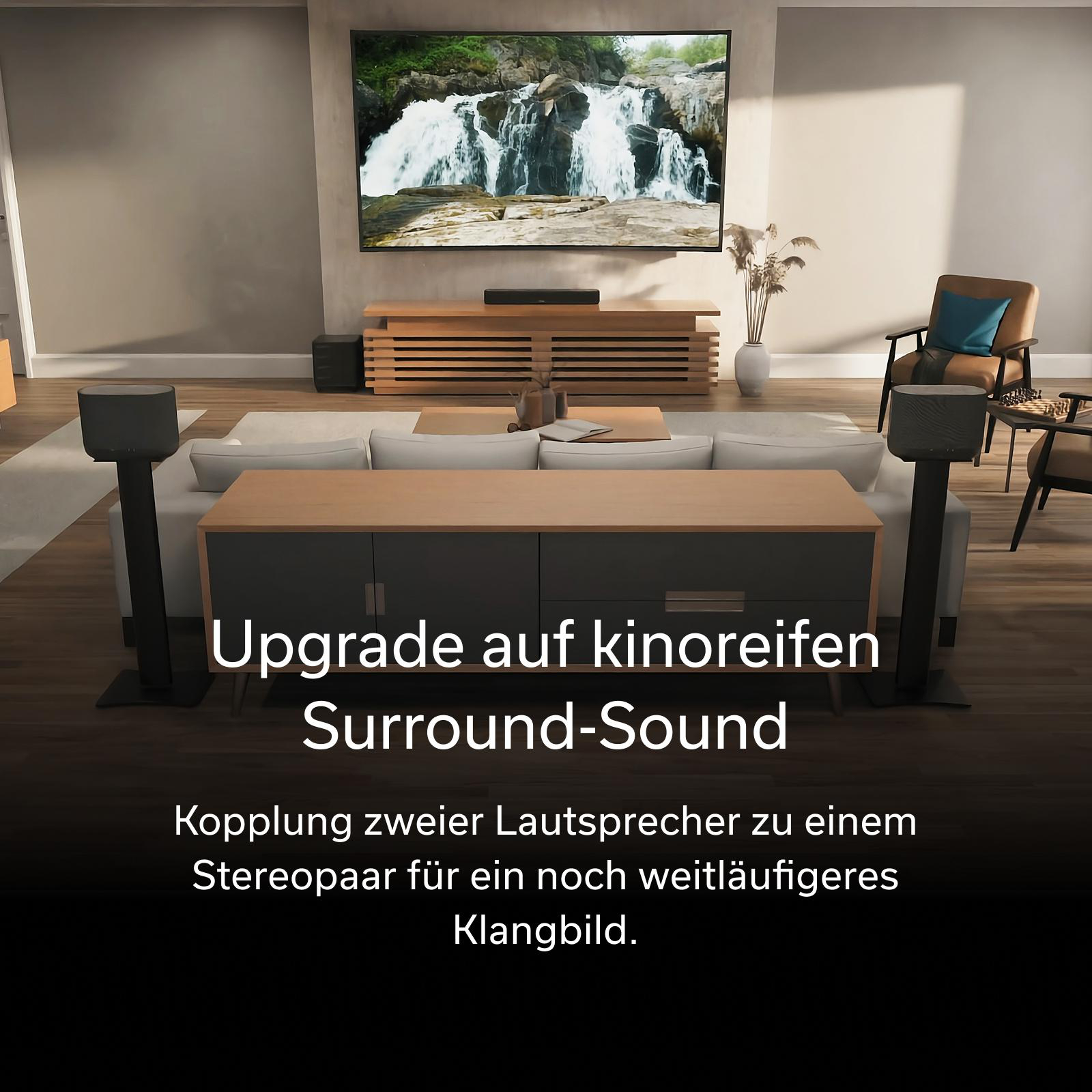 Ein Wohnzimmer mit Fernseher, Sofa und zwei Lautsprechern.