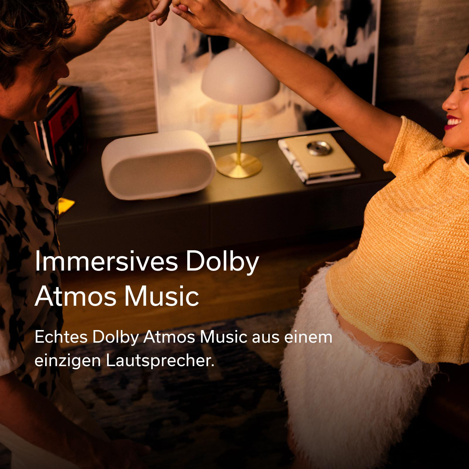 Ein Paar tanzt, ein Lautsprecher steht auf einem Tisch. Immersive Dolby Atmos Music.