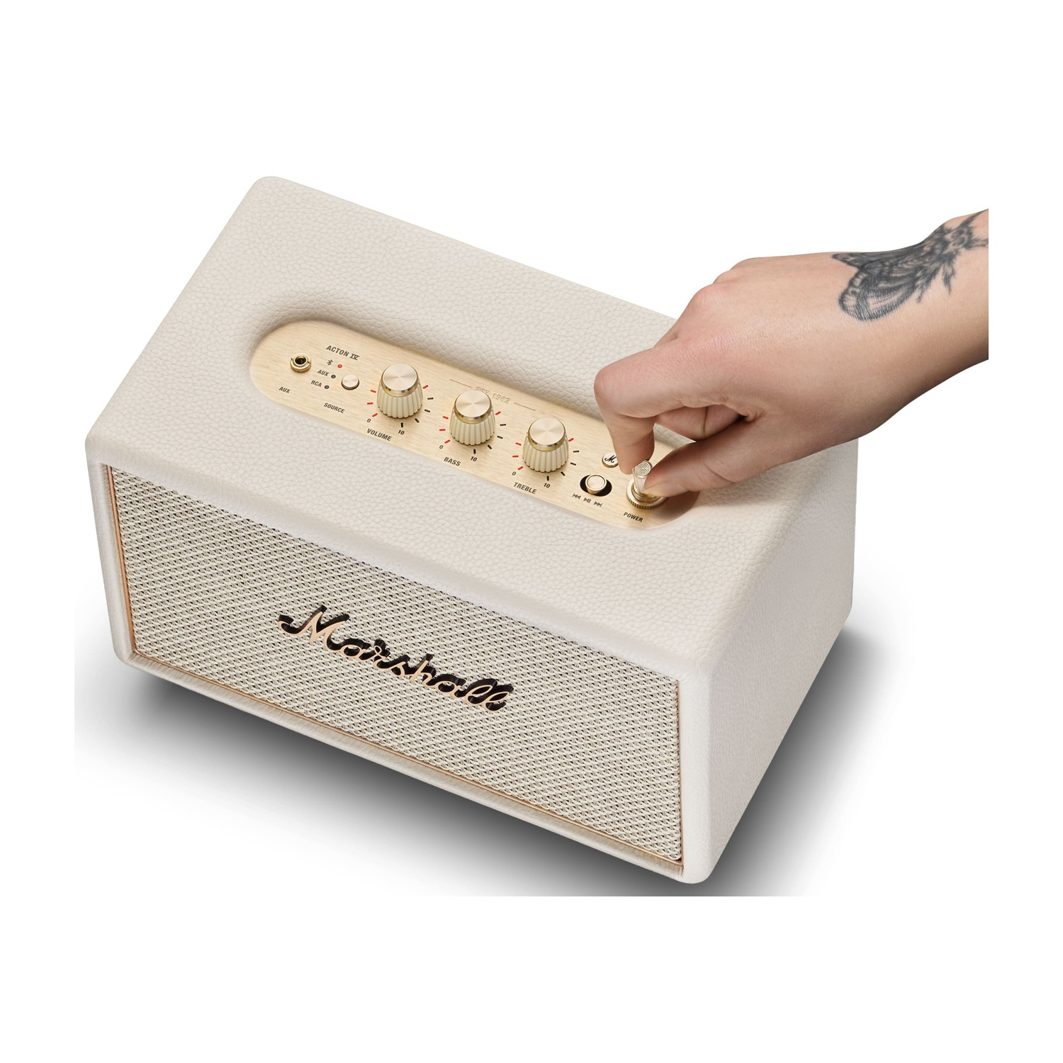 Una mano con tatuaggio gira la manopola su un altoparlante Marshall beige.
