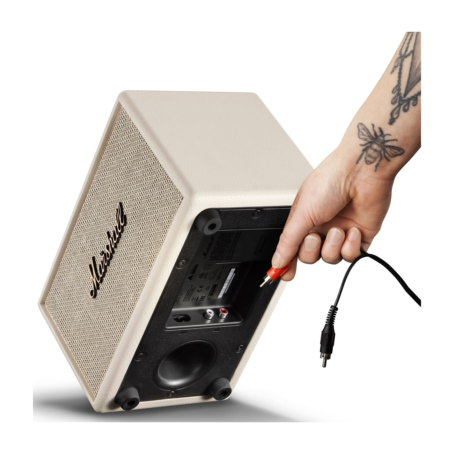 Una mano inserisce un connettore RCA rosso in un altoparlante Marshall bianco.