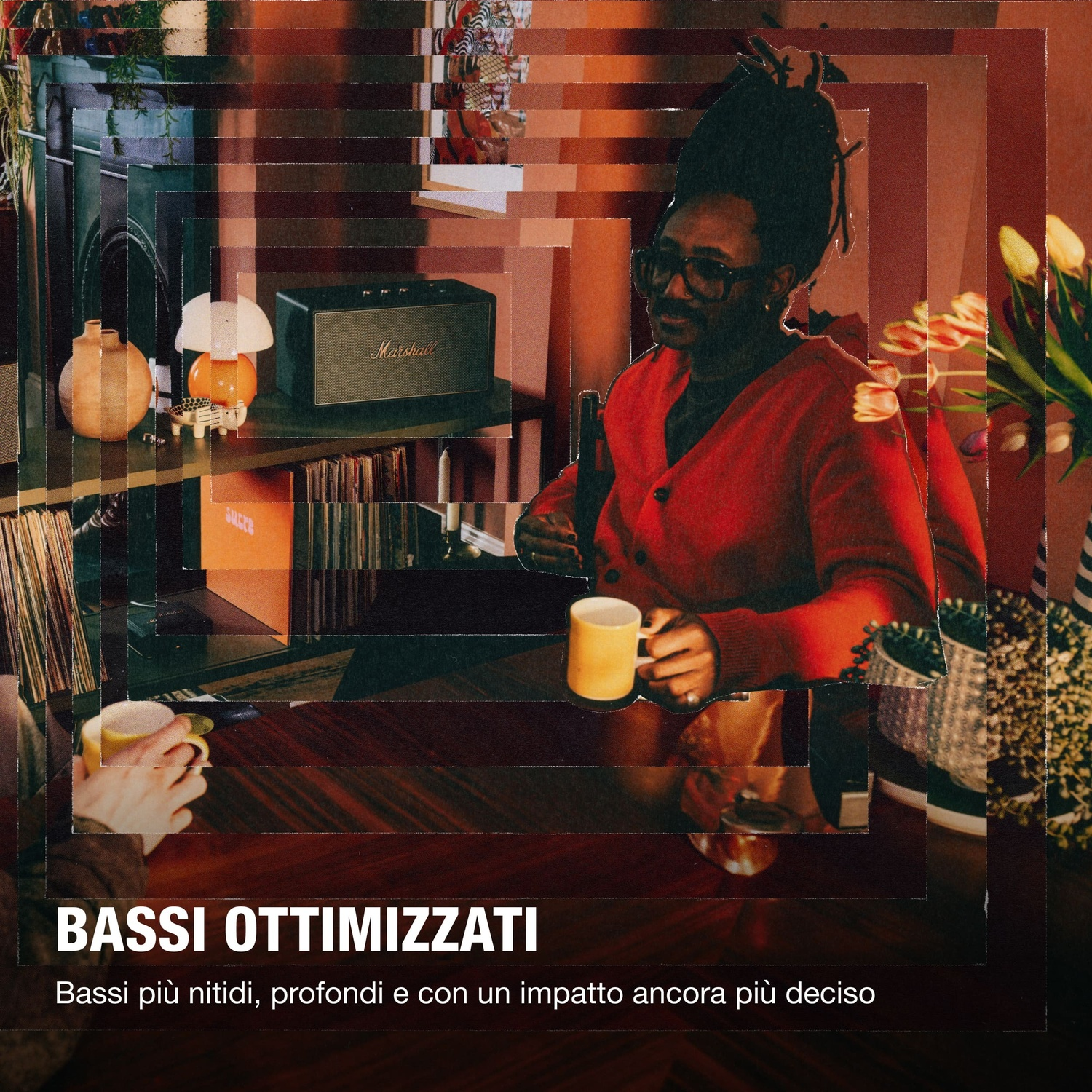 Uomo in cardigan rosso e occhiali beve caffè vicino a speaker Marshall.